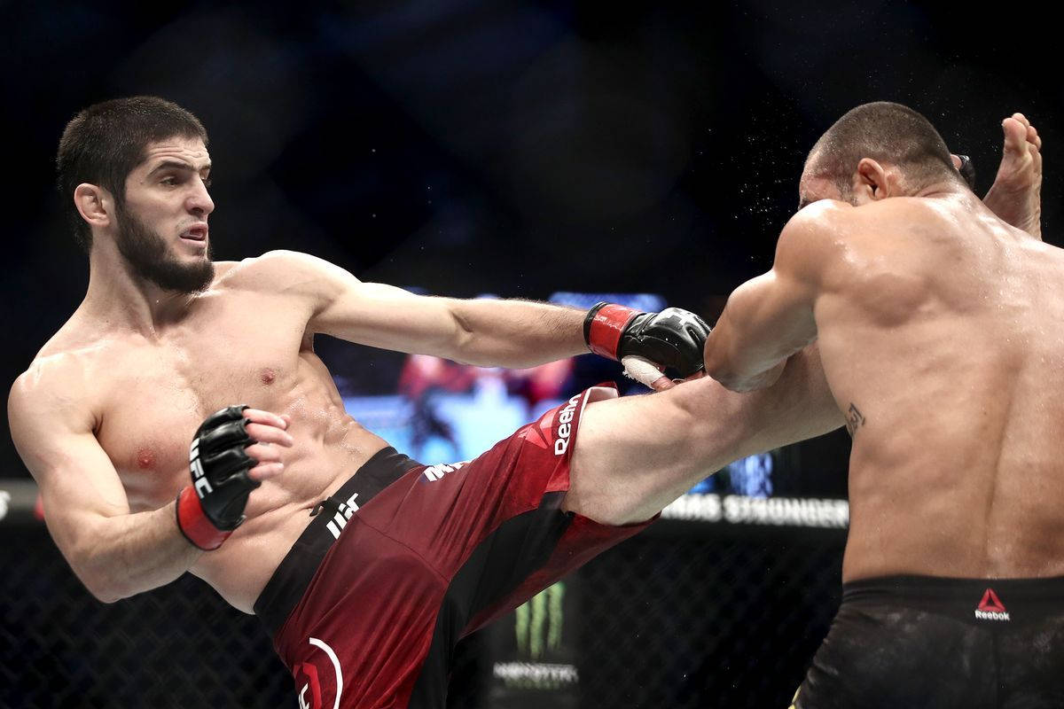 UFC 桌布 壁紙 — 一名拳手在光線充足的MMA籠內進行激烈比賽時，向對手使出高踢。