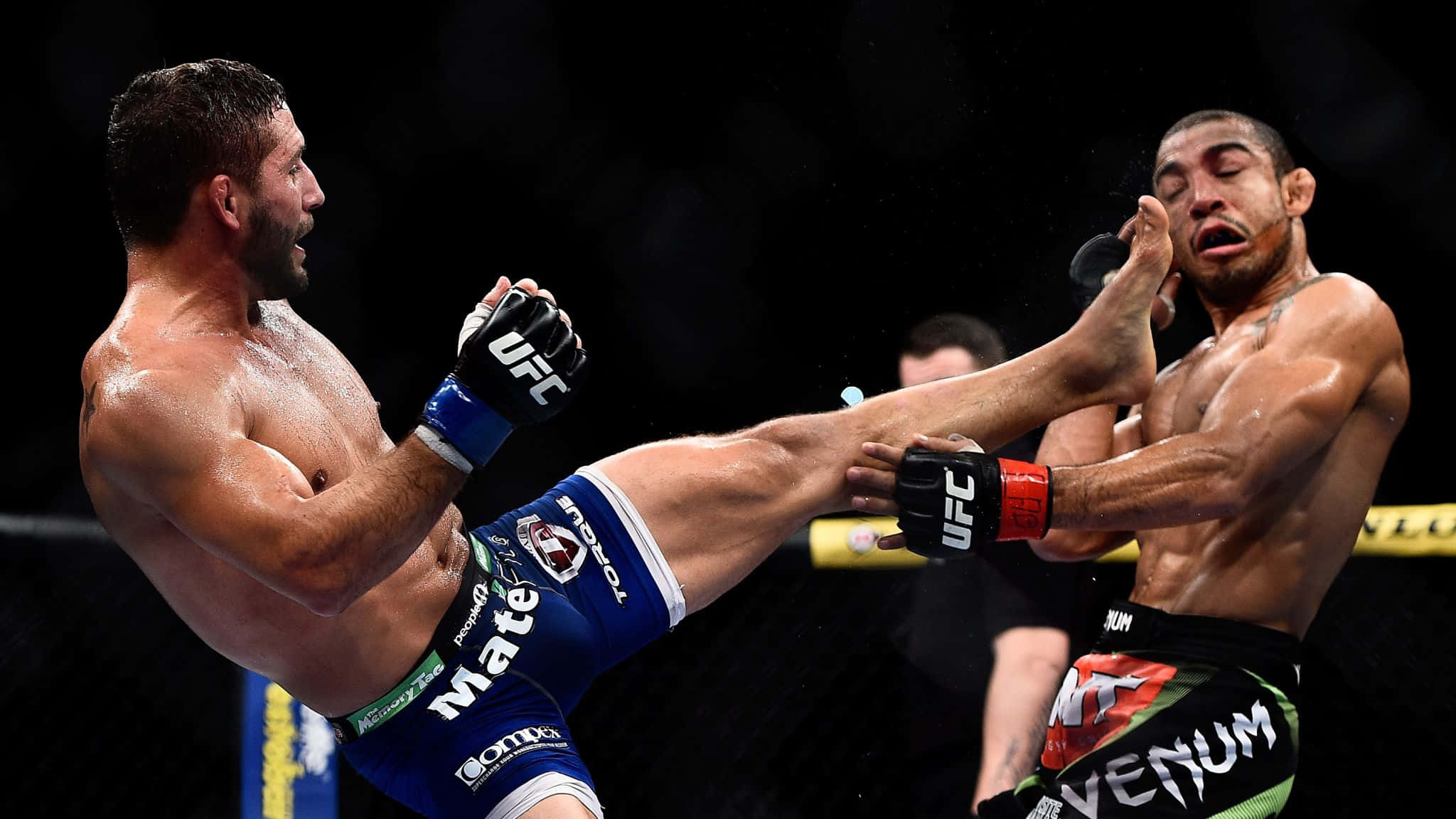 MMA 桌布 壁紙 — 一名拳手在明亮的場館燈光下，於UFC八角籠中向對手施展高踢。
