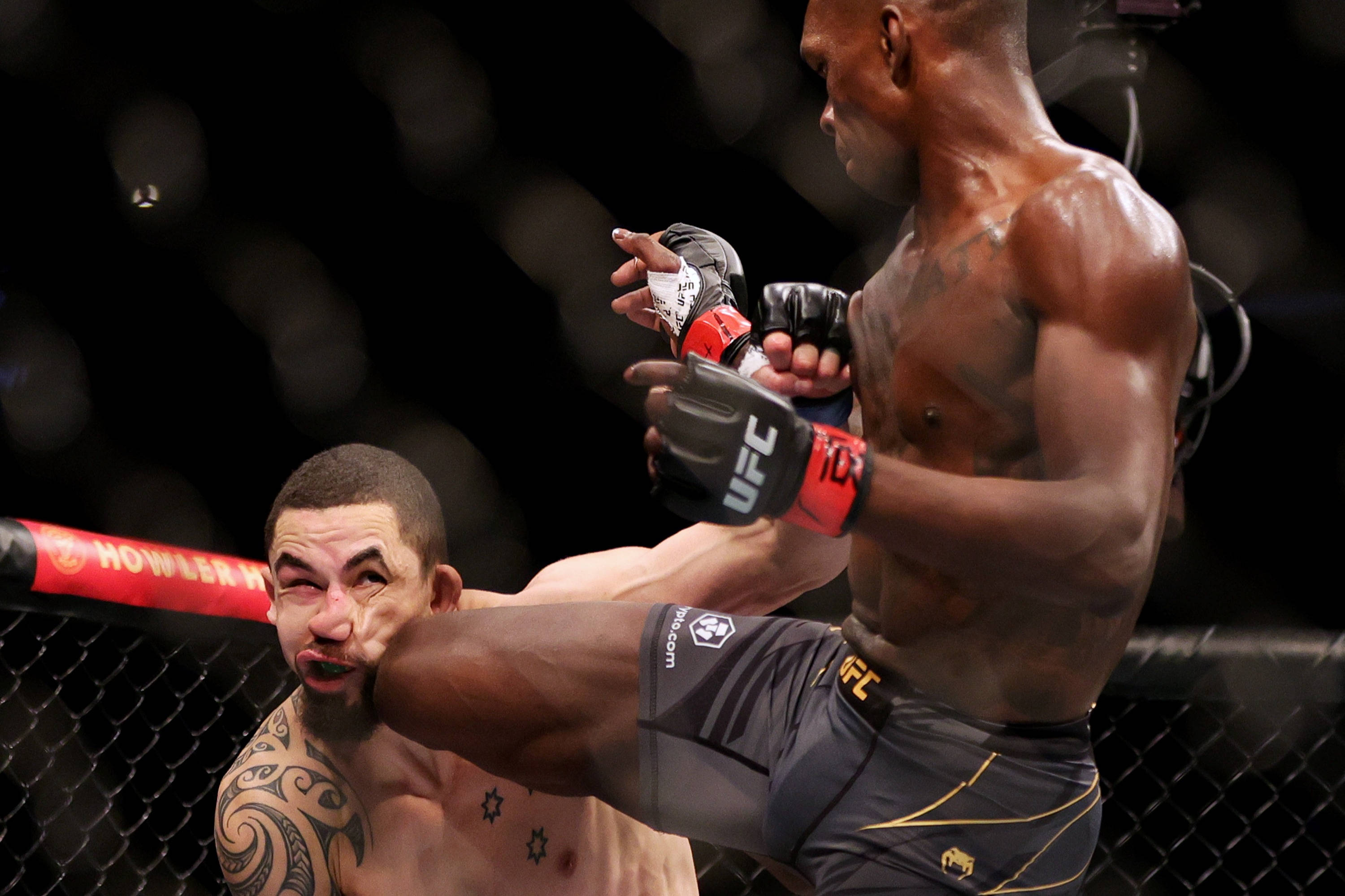 UFC 桌布 壁紙 — 一名拳手在明亮的場館燈光下，於UFC八角籠內向對手面部施以強力踢擊。