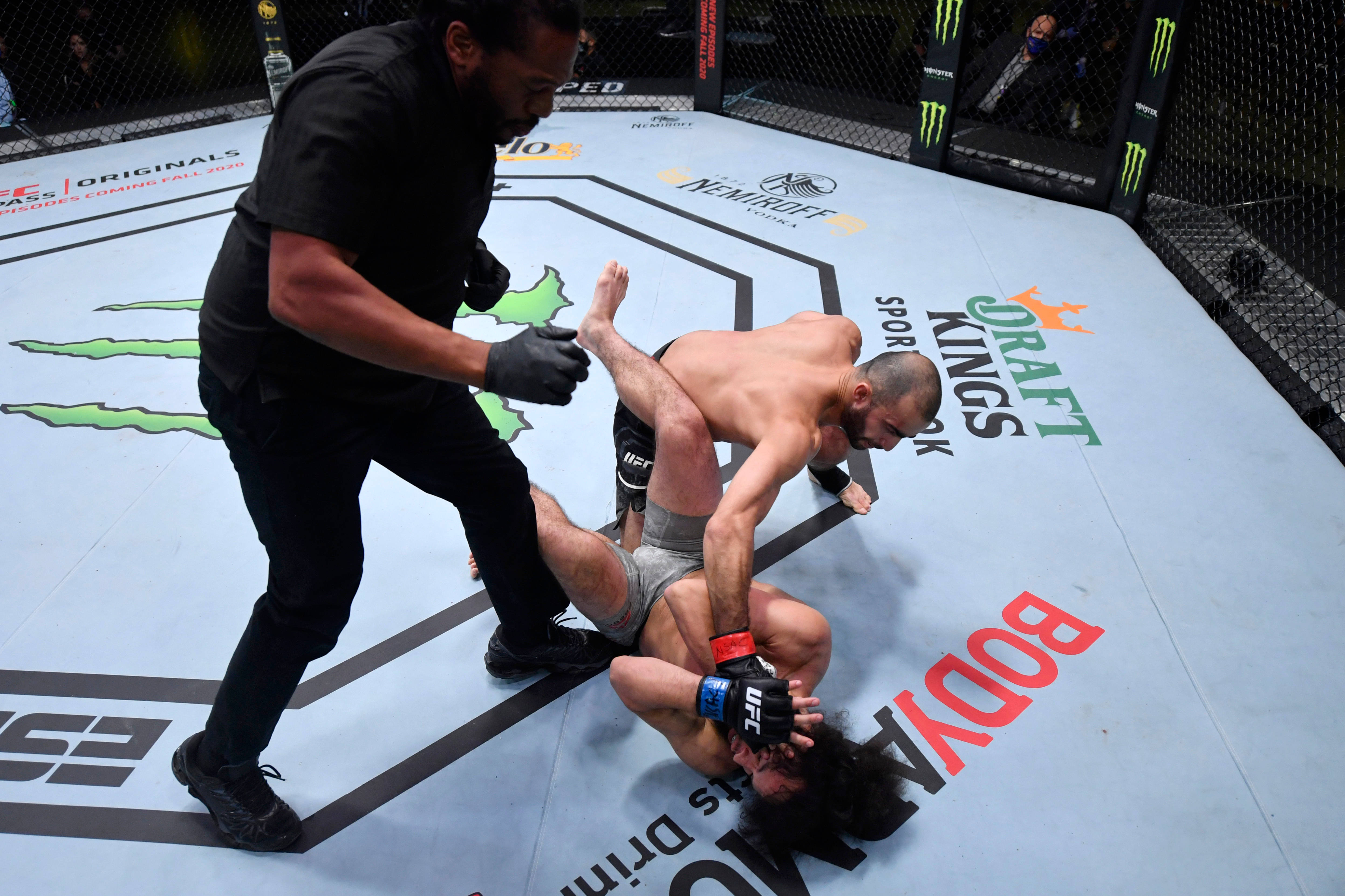 UFC 桌布 壁紙 — 一名拳手對對手施展降服技，裁判在UFC八角籠內近距離監控。