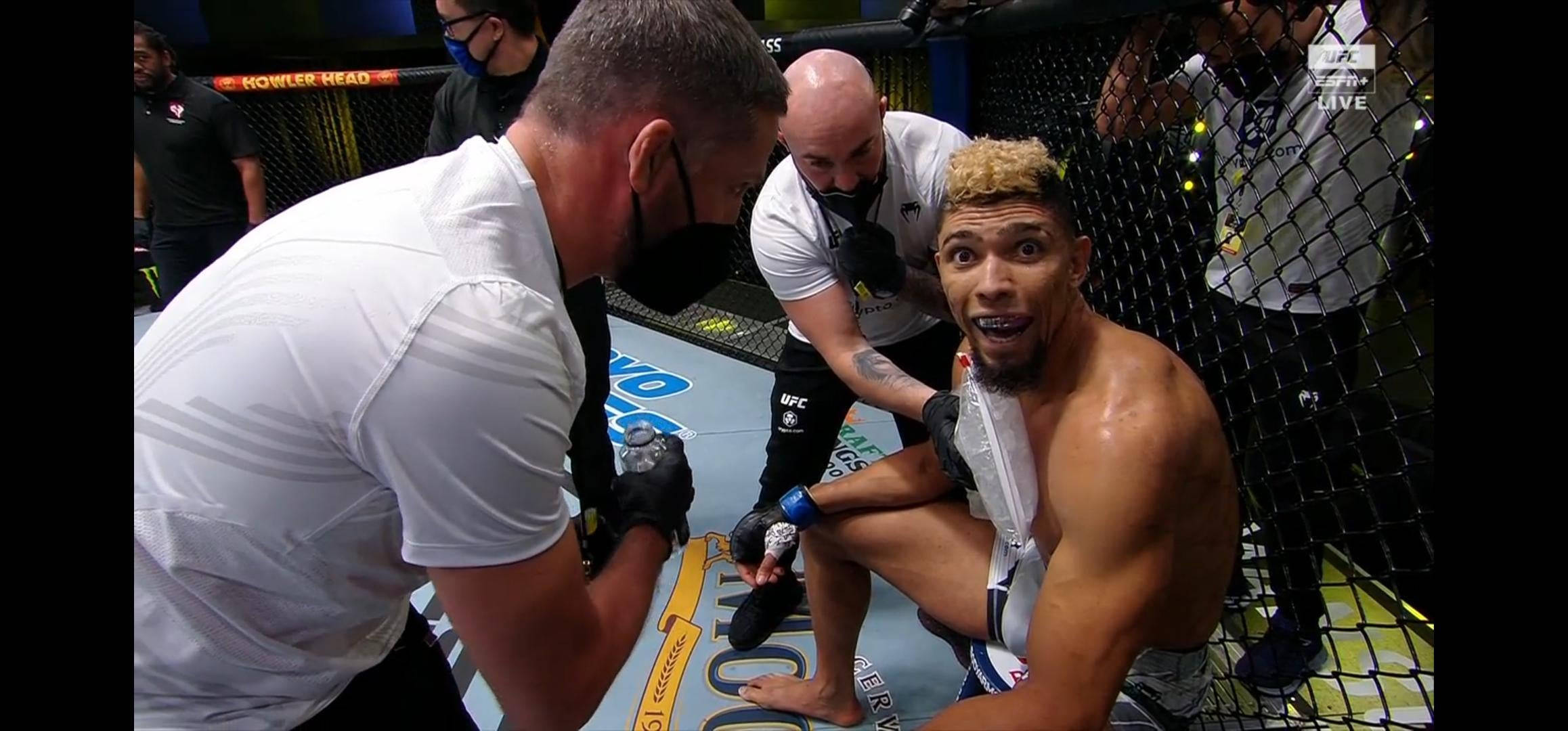 MMA 桌布 壁紙 — 一名拳手疲憊地坐在八角籠中，醫護人員正在處理他在UFC比賽中受傷的腿。