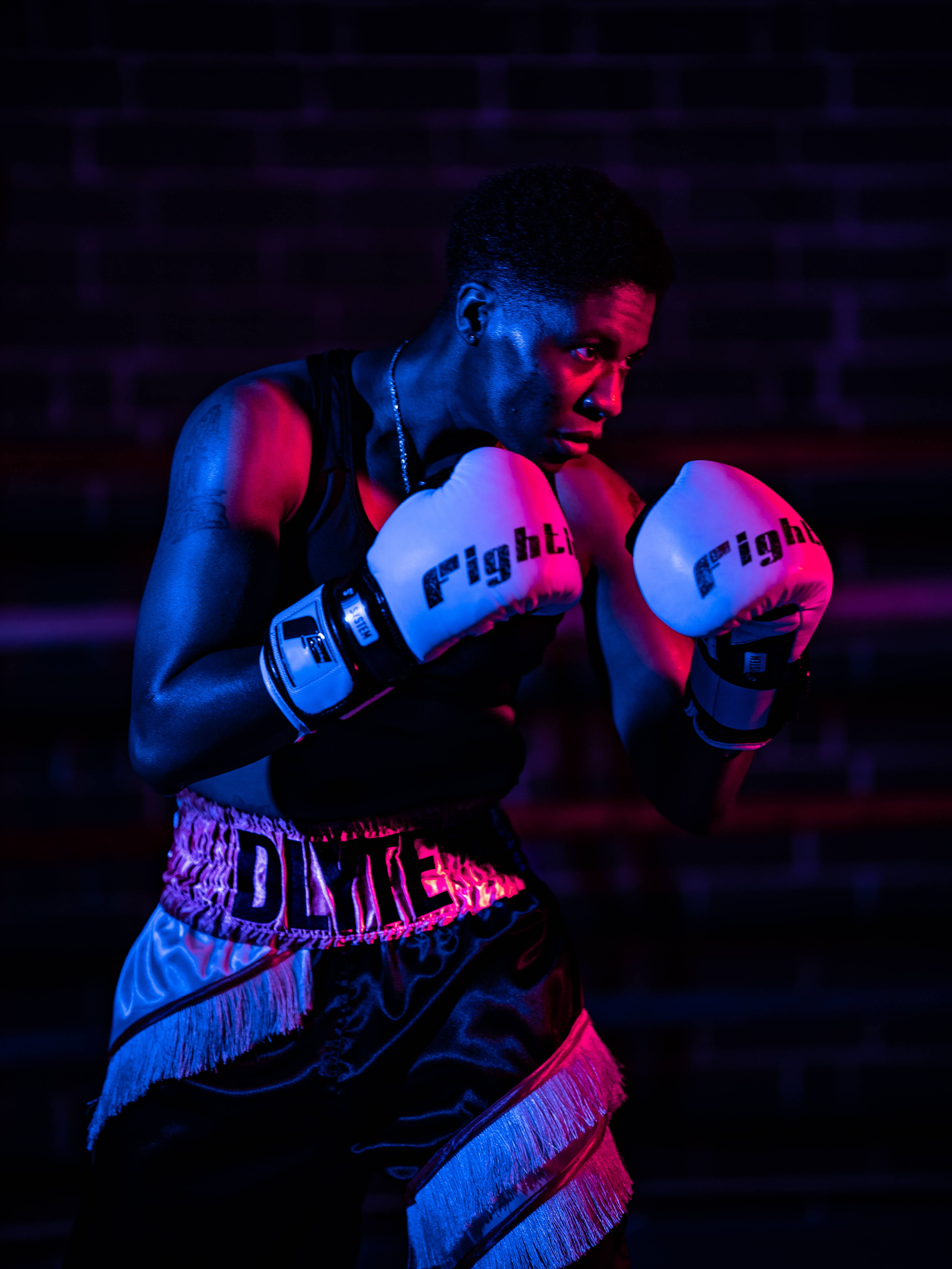 Cool Boxing 桌布 壁紙 — 一名拳擊手在戲劇性的紅藍燈光下，以磚牆為背景擺出戰鬥姿勢。