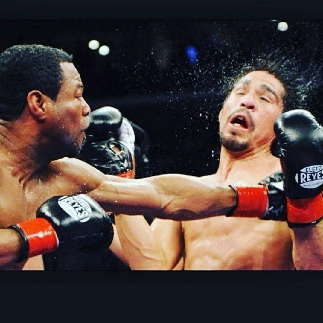 Boxing 桌布 壁紙 — 一名拳擊手在明亮的場館燈光下，於被雨水濺濕的擂台上向對手打出強力一拳。