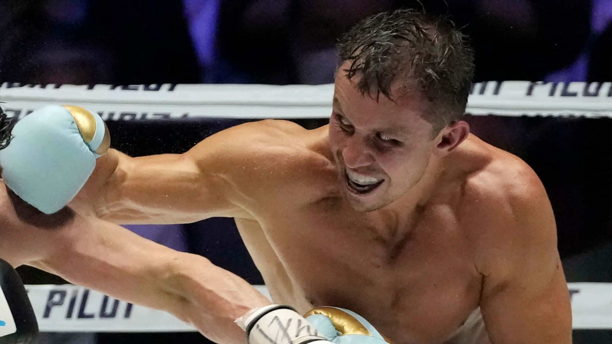 Boxing 桌布 壁紙 — 一名拳擊手在燈光明亮的擂台上打出強力一拳，汗水飛濺，專注力極強。