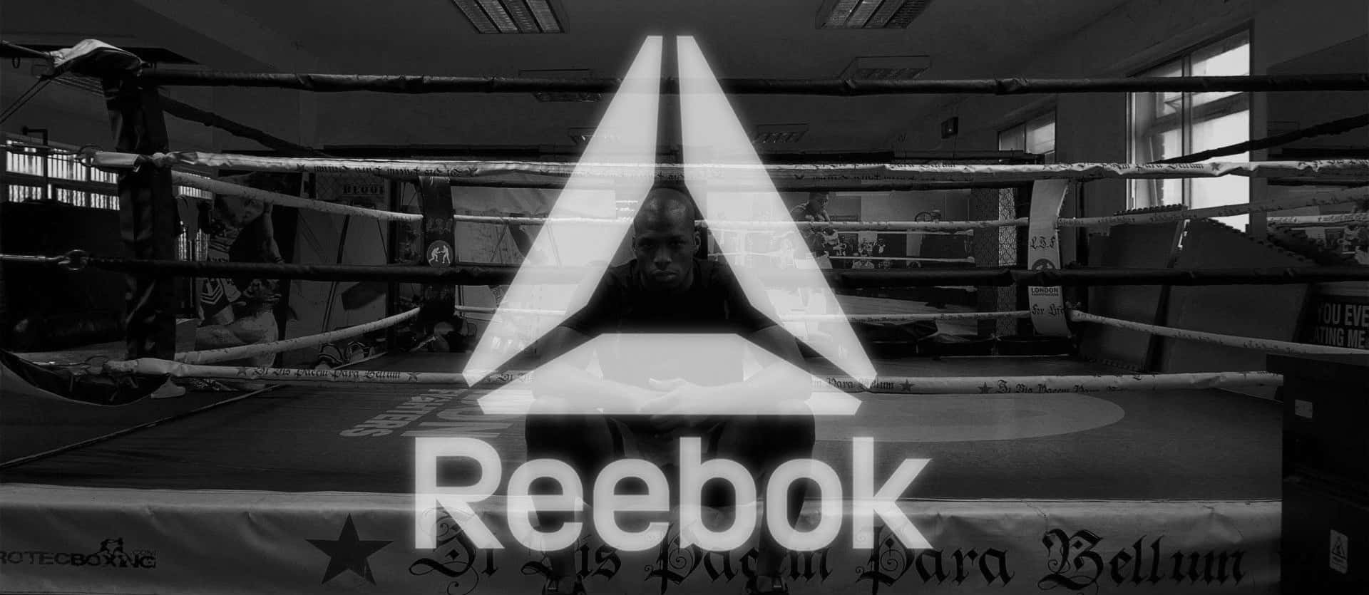 Reebok 桌布 壁紙 — 一名拳擊手坐在燈光昏暗的擂台上，發光的Reebok標誌以單色疊加在場景上。