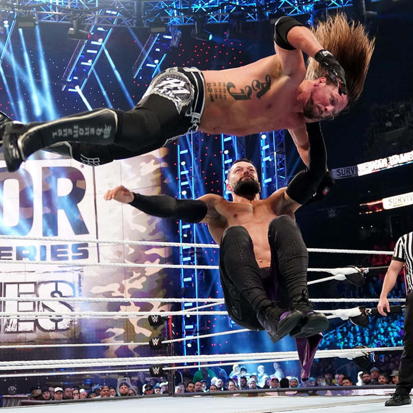 WWE 桌布 壁紙 — 一名摔角手在半空中躍起，在燈光明亮的摔角場內對對手施展高空飛行動作。