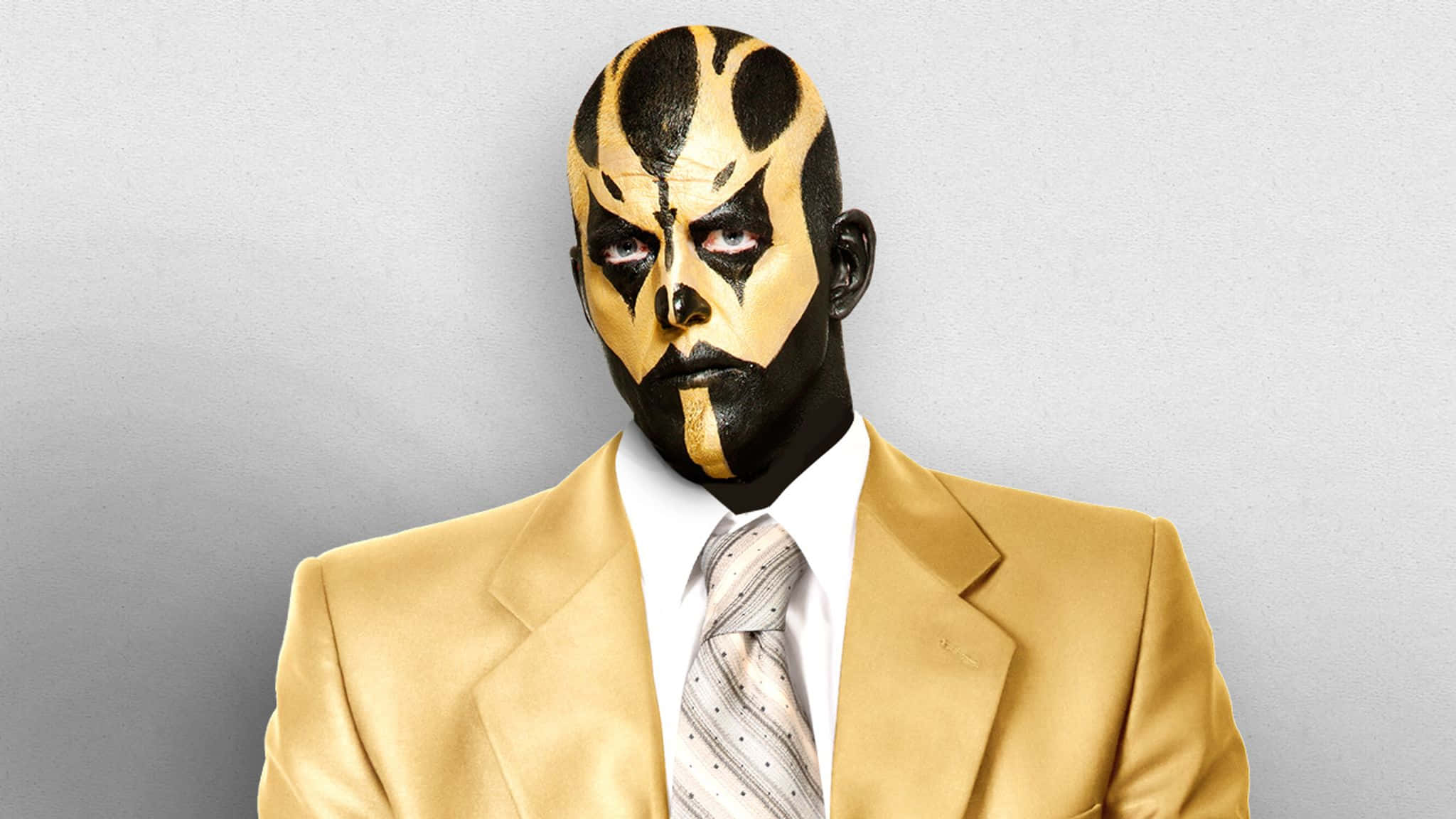 WWE 桌布 壁紙 — 一名摔角手帶有醒目的黑色和金色面部彩繪，穿著相配的金色西裝，在純灰色背景前凝視著。