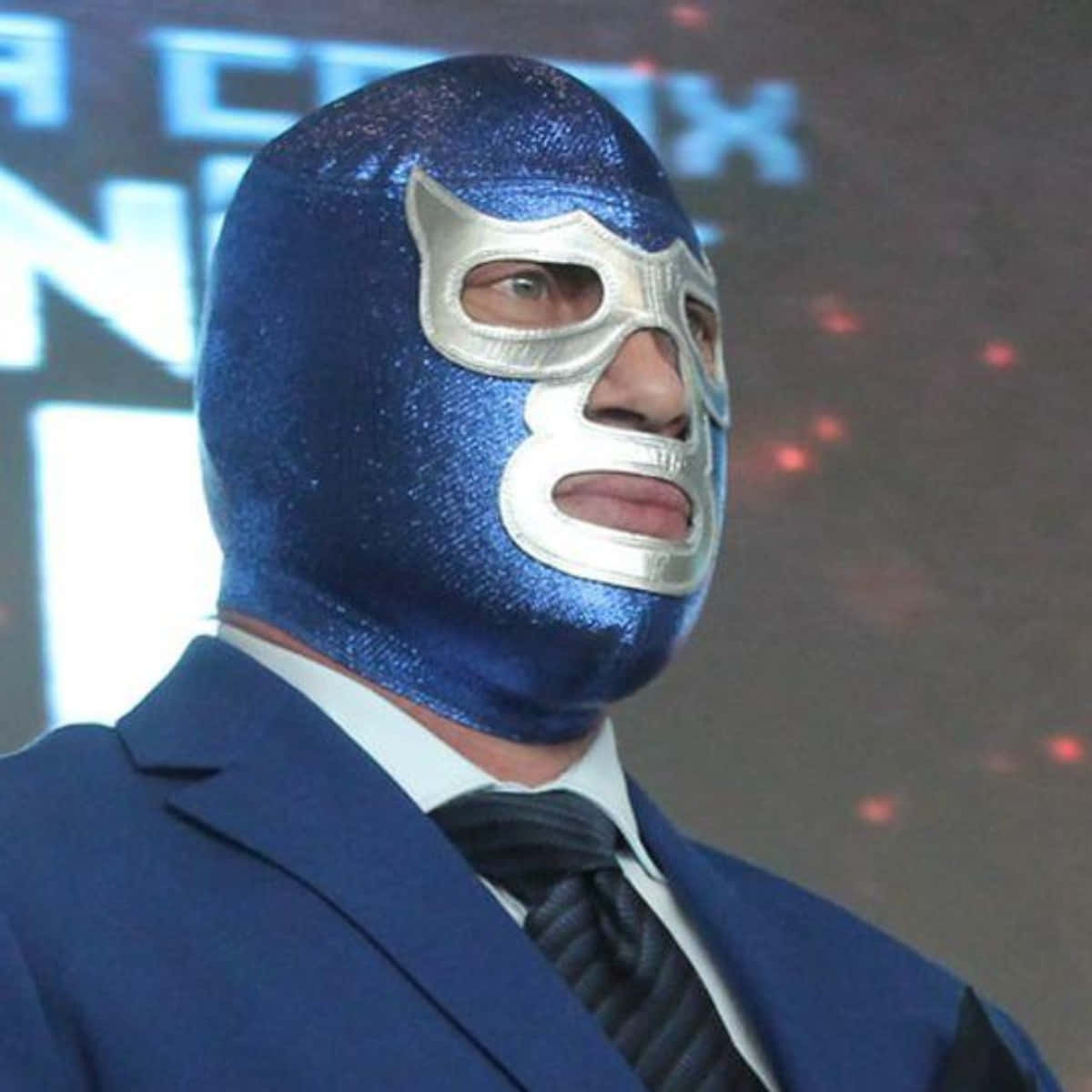 Mexican 桌布 壁紙 — 一名摔角手戴著閃閃發光的藍色面具和服裝，在場館燈光下擺好姿勢，身後有發光文字。