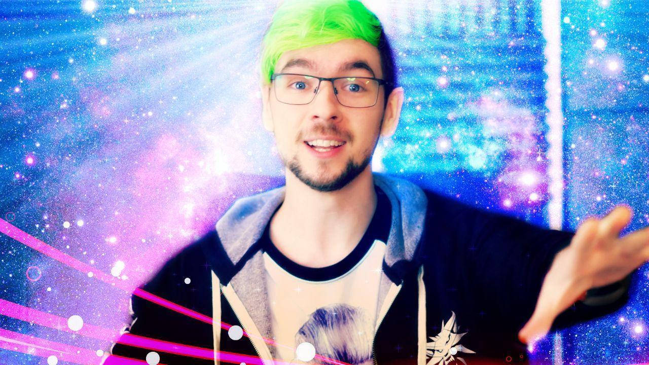 Jacksepticeye 桌布 壁紙 — 一名擁有亮綠色頭髮和眼鏡的男子，在帶有發光粉紅色條紋的宇宙銀河背景中微笑。