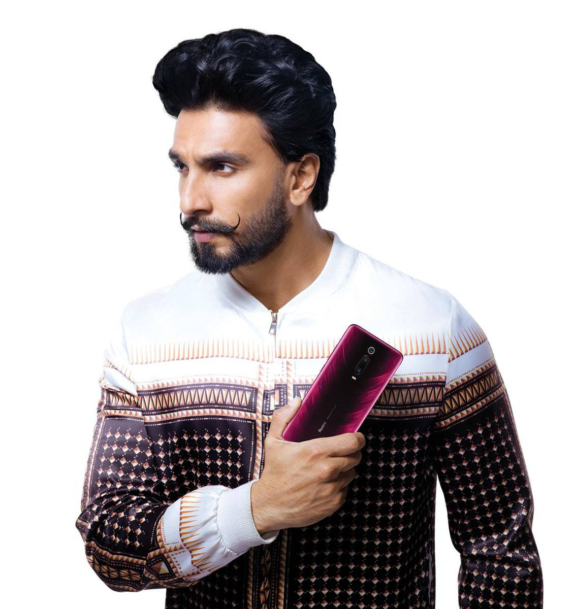 Ranveer Singh 桌布 壁紙 — 一名擁有時尚黑髮和鬍鬚的男子，在純白背景前手持亮面洋紅色手機。