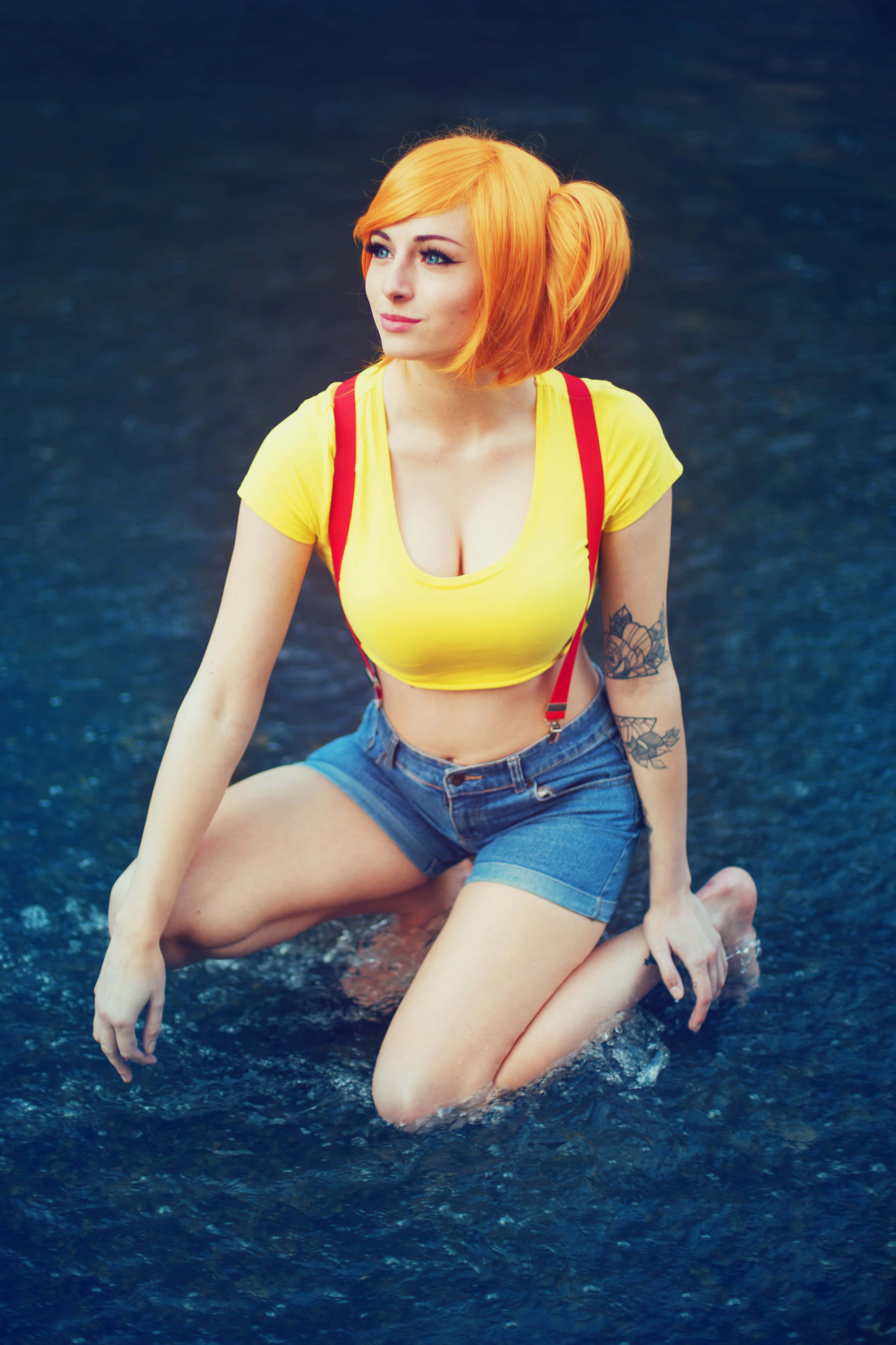Gaming Cosplay 桌布 壁紙 — 一名擁有橙色辮子的女性跪在暗水中，身穿黃色上衣和帶紅色吊帶的牛仔短褲。