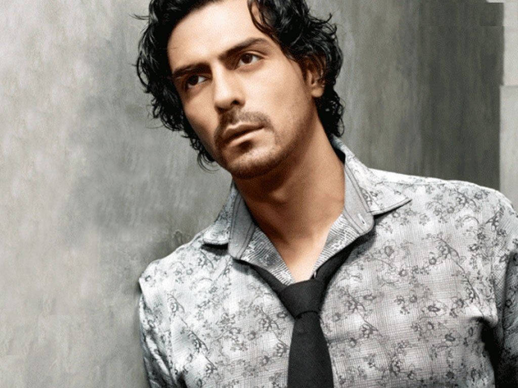Arjun Rampal 桌布 壁紙 — 一名擁有深色捲髮和鬍鬚的男子，穿著圖案襯衫和黑色領帶，背景是帶有紋理的灰色牆壁。