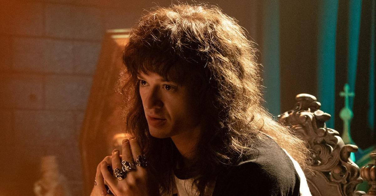  壁紙 — 一名擁有豐盈捲髮的男子坐在華麗的椅子上，沐浴在溫暖的金色光線中，背景是石牆和藍綠色窗簾。
