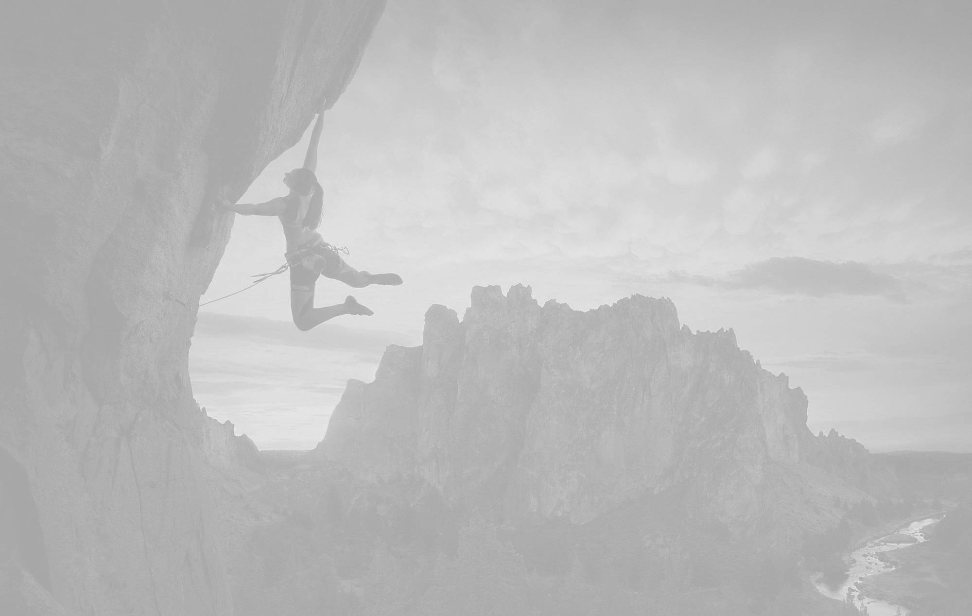 Climbing 桌布 壁紙 — 一名攀岩者懸掛在懸崖面上，背景是霧氣瀰漫的山巒，以單色呈現。