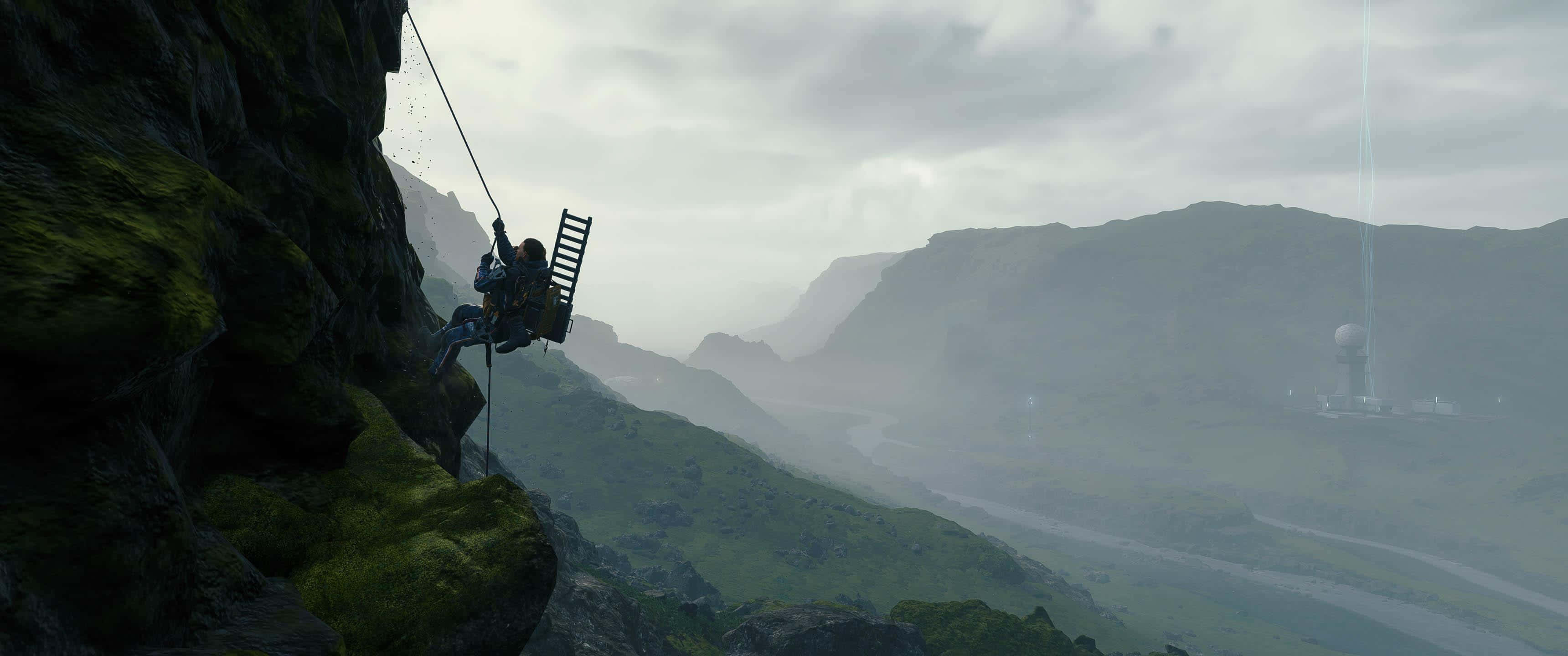 3440x1440p Death Stranding 桌布 壁紙 — 一名攀岩者用梯子從長滿苔蘚的懸崖面下降，下方是霧氣瀰漫的山谷和遠處的雷達塔。