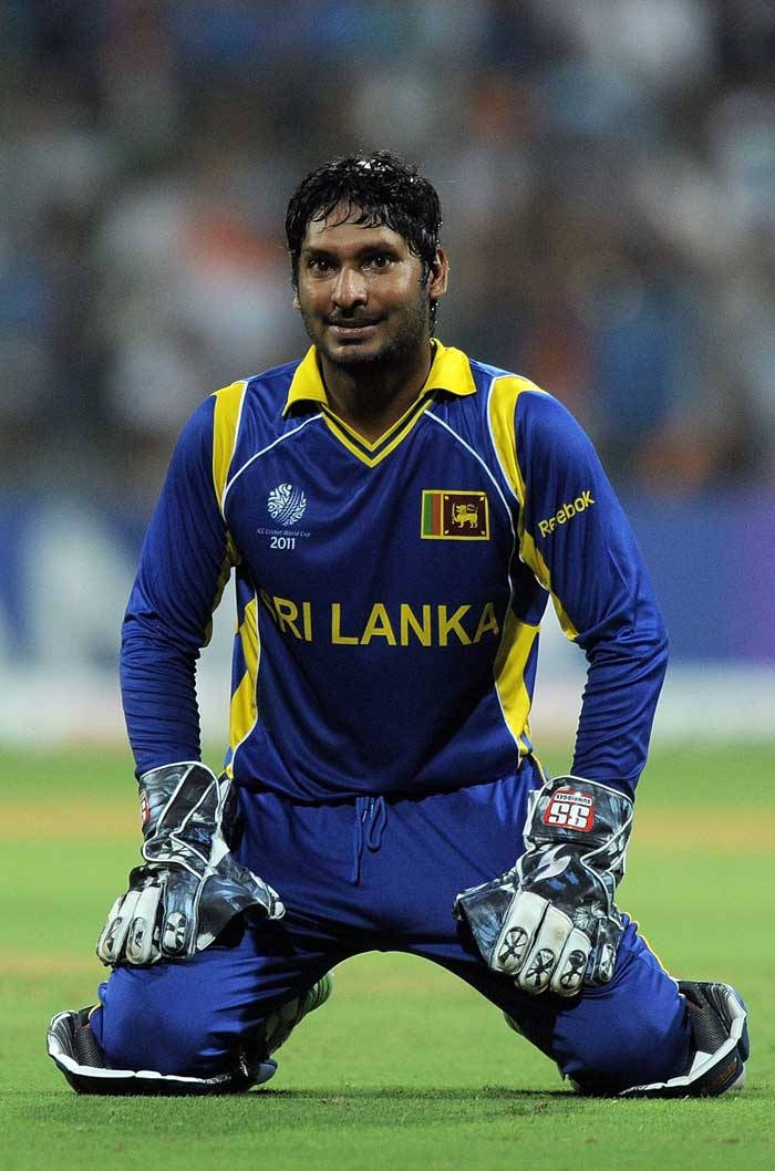 Sri Lanka Cricket 桌布 壁紙 — 一名斯里蘭卡板球運動員在體育場燈光下，穿著藍黃色裝備跪在綠色場地上。