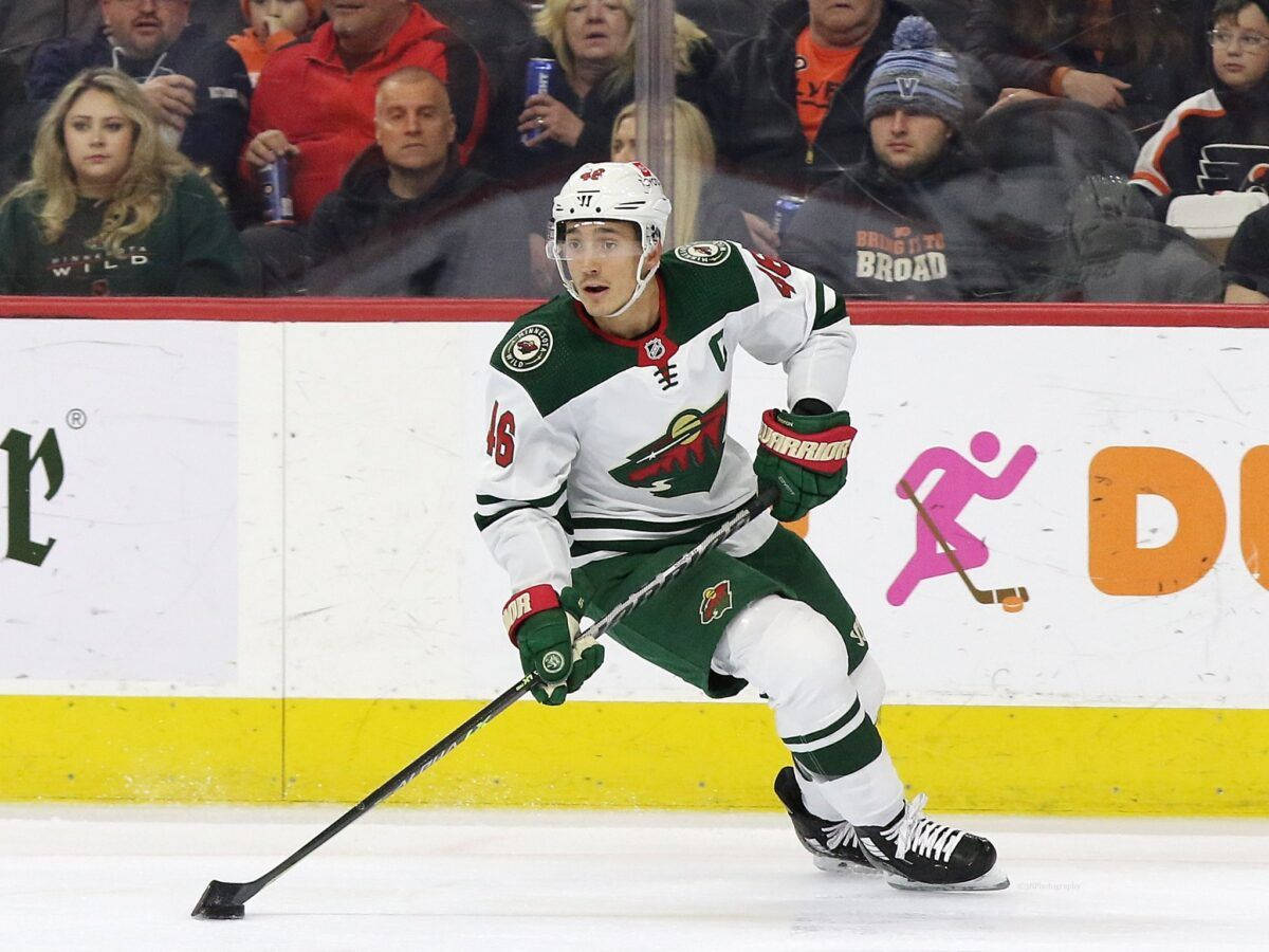 hockey 桌布 壁紙 — 一名明尼蘇達荒野冰球球員穿著綠色和白色裝備，在比賽中手持冰球在冰上激烈滑行。