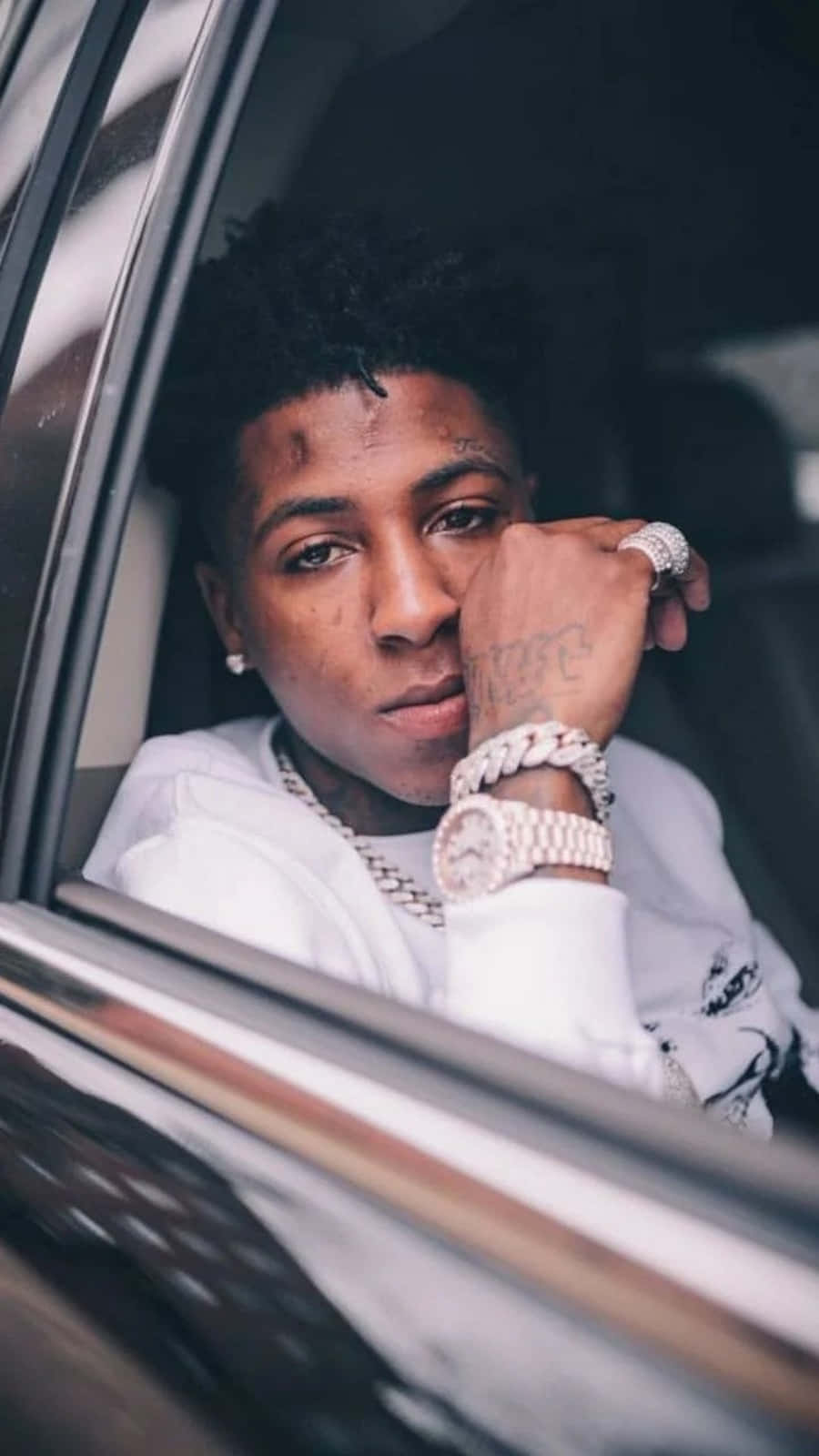 NBA YoungBoy 桌布 壁紙 — 一名有刺青和珠寶的年輕男子穿著白色連帽衫和金鍊，從車窗探出頭來。