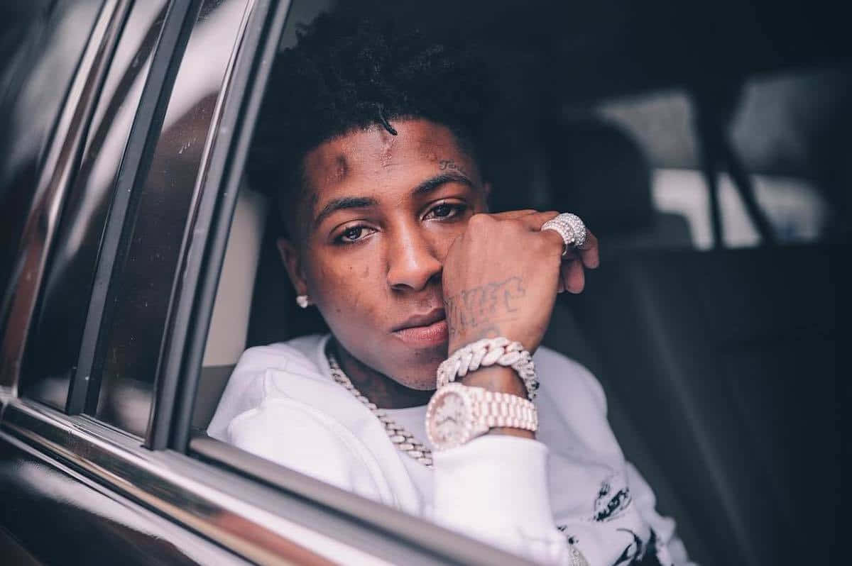 Youngboy 桌布 壁紙 — 一名有刺青和珠寶的年輕男子穿著白色連帽衫和金鏈，從車窗探出身子。
