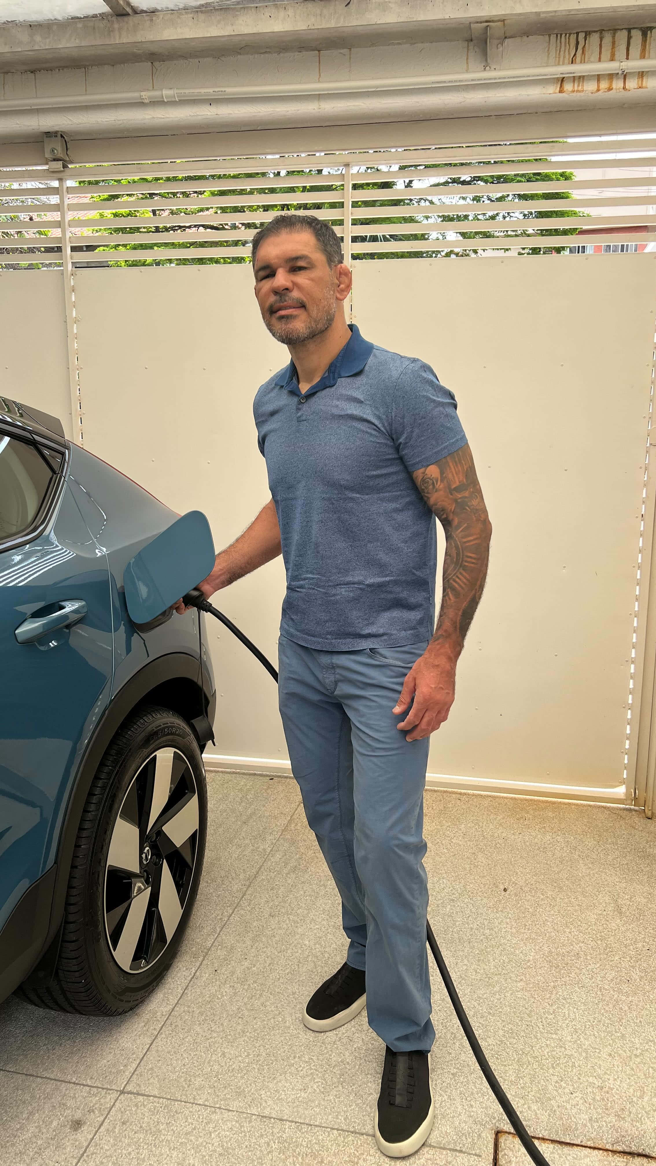 Celebrity 桌布 壁紙 — 一名有刺青的男子在有蓋天井下的充電站為電動車充電。