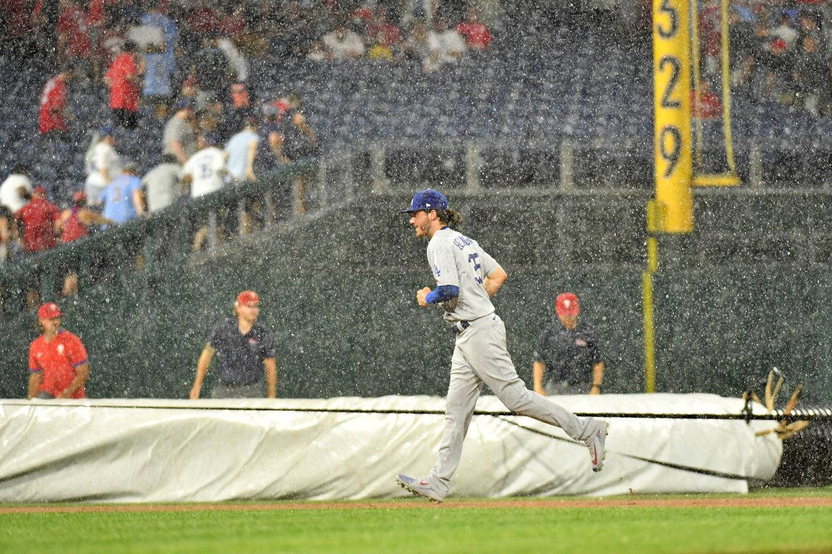 Phillies 桌布 壁紙 — 一名棒球運動員在濕滑的場地上衝刺，觀眾在球場燈光下從模糊的看台觀看。