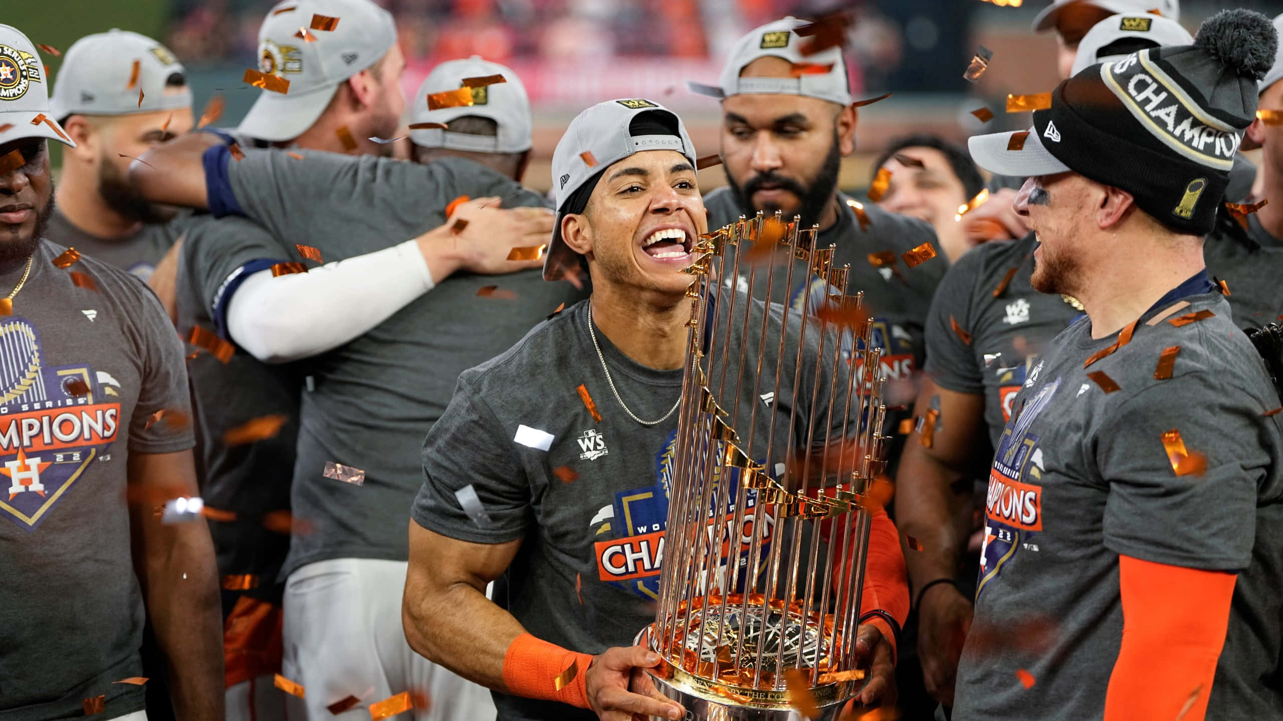 Astros 桌布 壁紙 — 一名棒球運動員滿臉笑容地拿著閃閃發光的獎盃，隊友們在周圍飄落的五彩紙屑中慶祝。