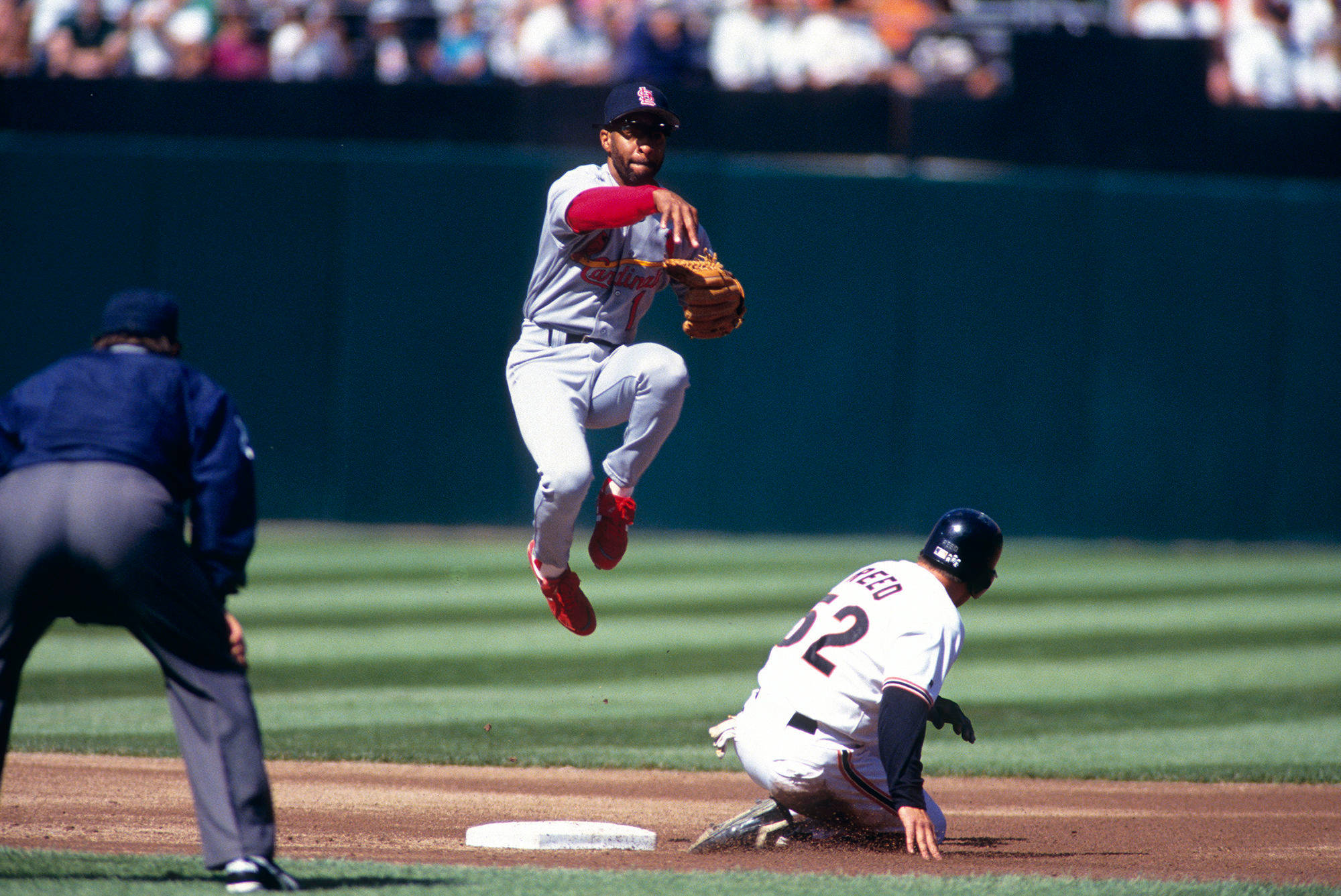 Ozzie Smith 桌布 壁紙 — 一名棒球選手在陽光明媚的日間比賽中跳起，試圖觸殺滑向二壘的跑壘員。