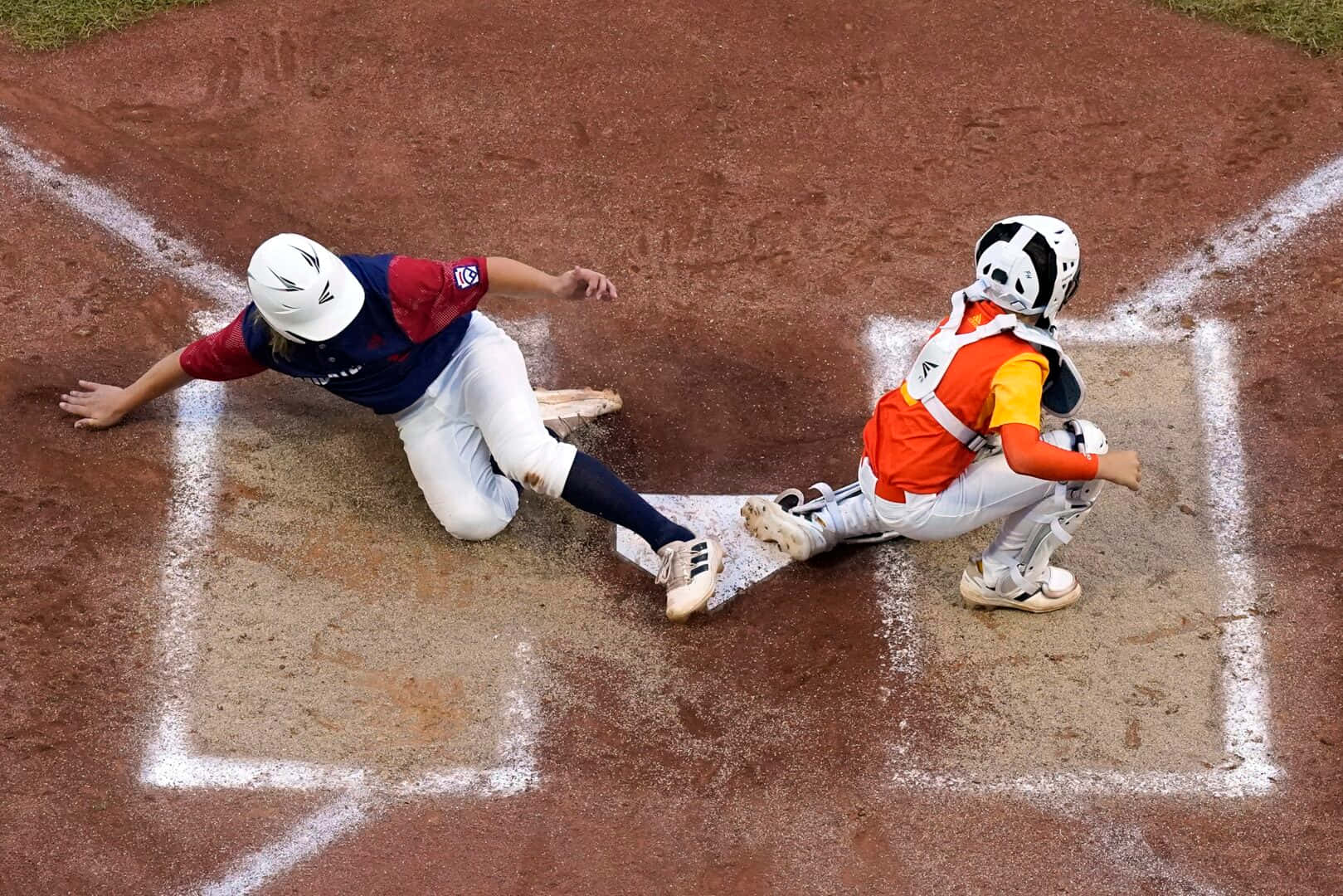 Little League Baseball 桌布 壁紙 — 一名棒球選手頭部滑進本壘，而身穿橙色裝備的捕手飛撲試圖觸殺她。