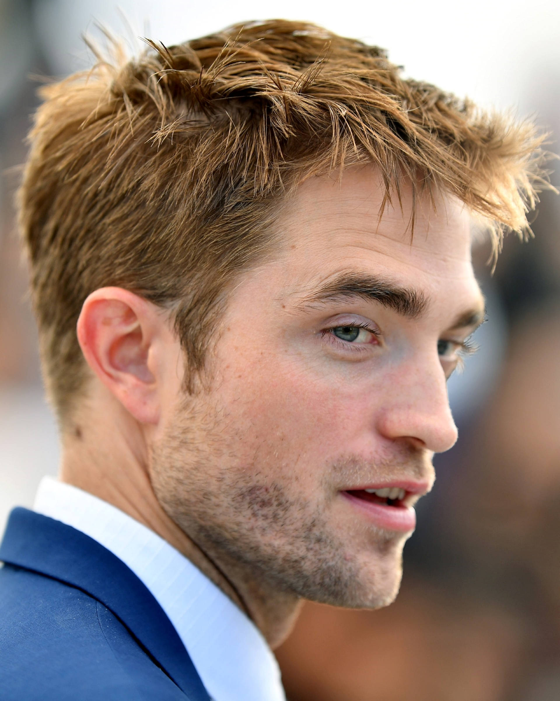Robert Pattinson 桌布 壁紙 — 一名棕色亂髮、鬍渣男人的特寫肖像，身穿藍色西裝和白色襯衫。