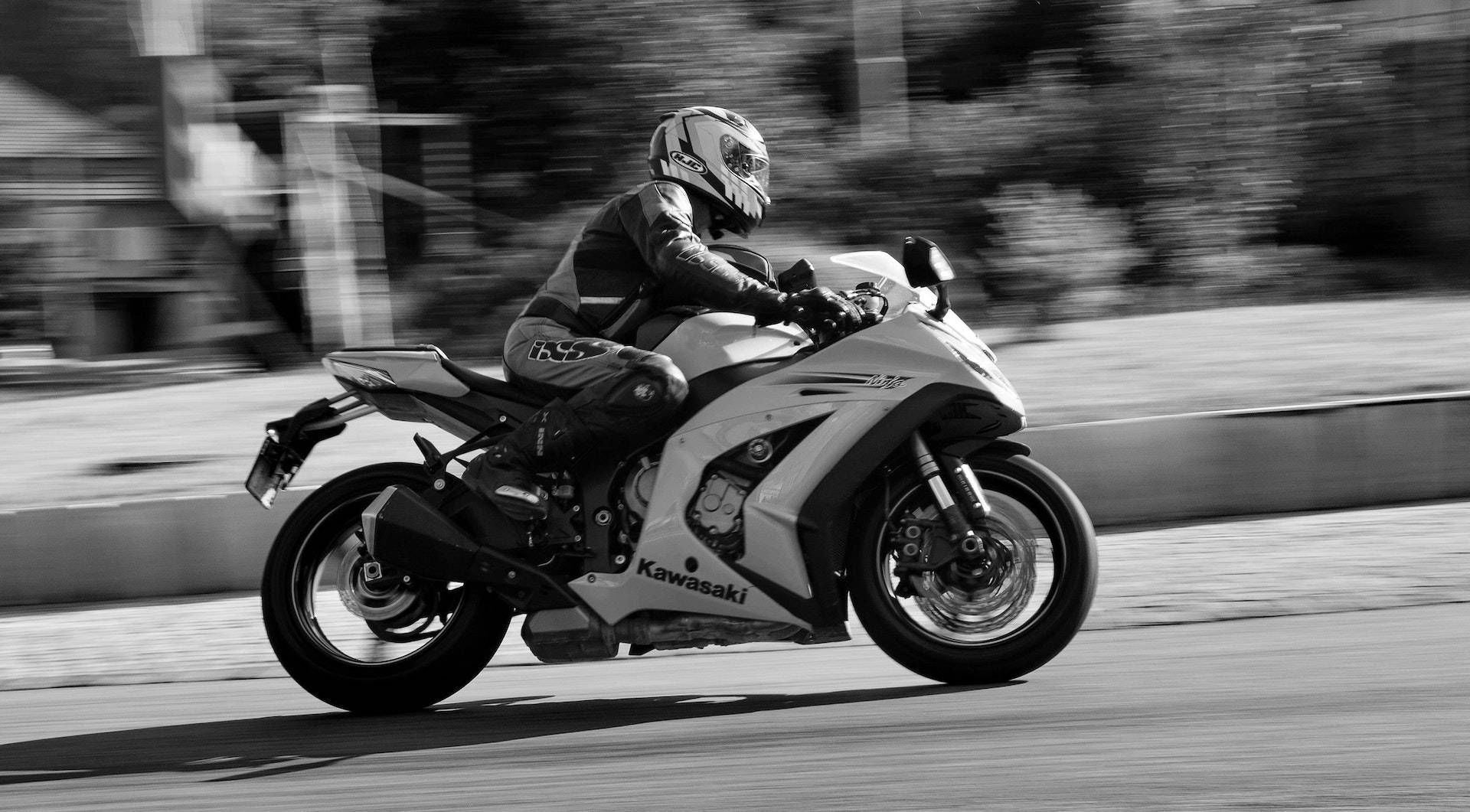 Speed 桌布 壁紙 — 一名機車手在川崎跑車上傾斜入彎，以高速黑白動態模糊捕捉。