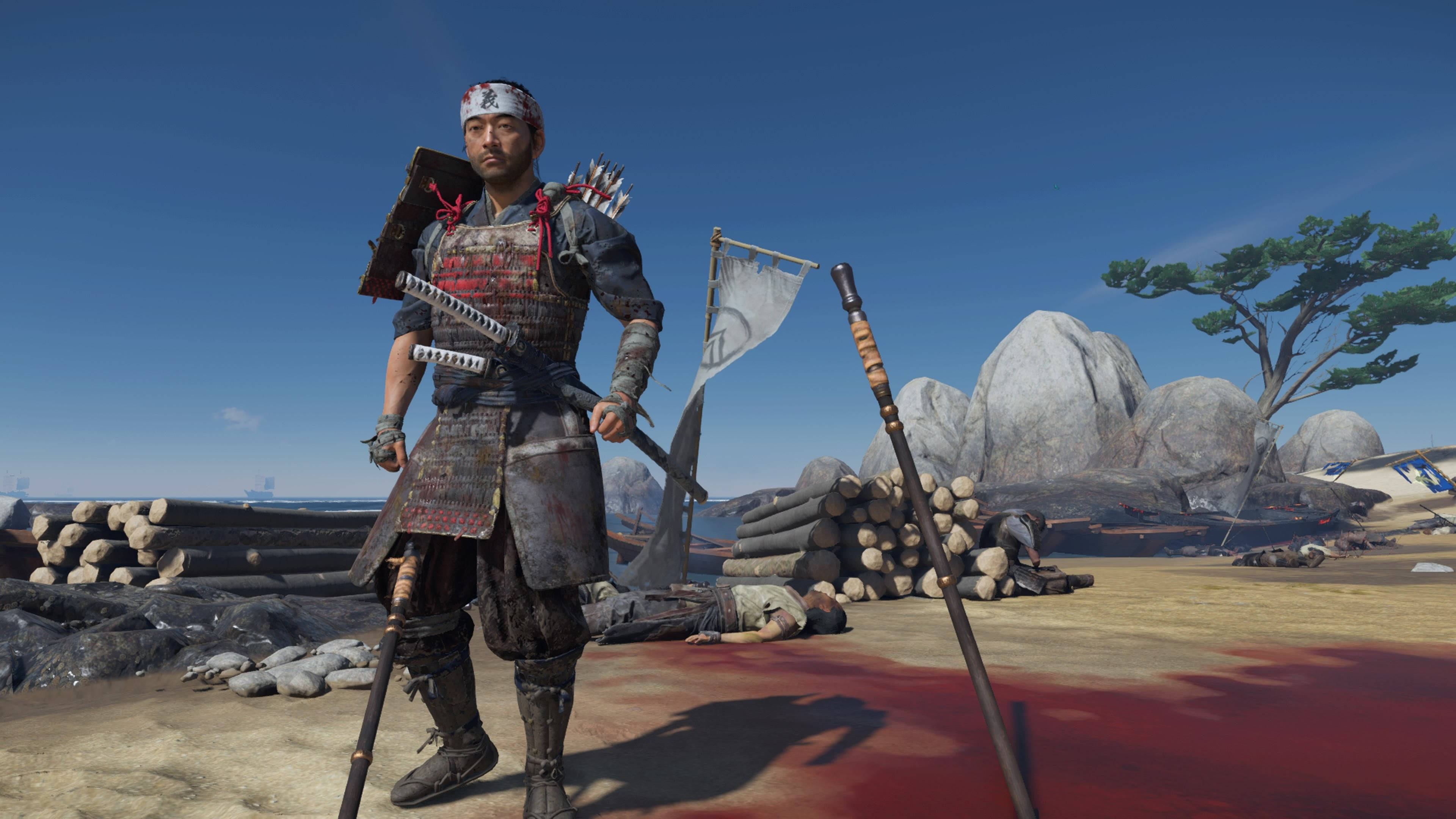 對馬戰鬼 桌布 壁紙 — 一名武士戰士站在血跡斑斑的田野上，手持劍，身後有倒下的敵人和原木，頭頂是清澈的藍天。