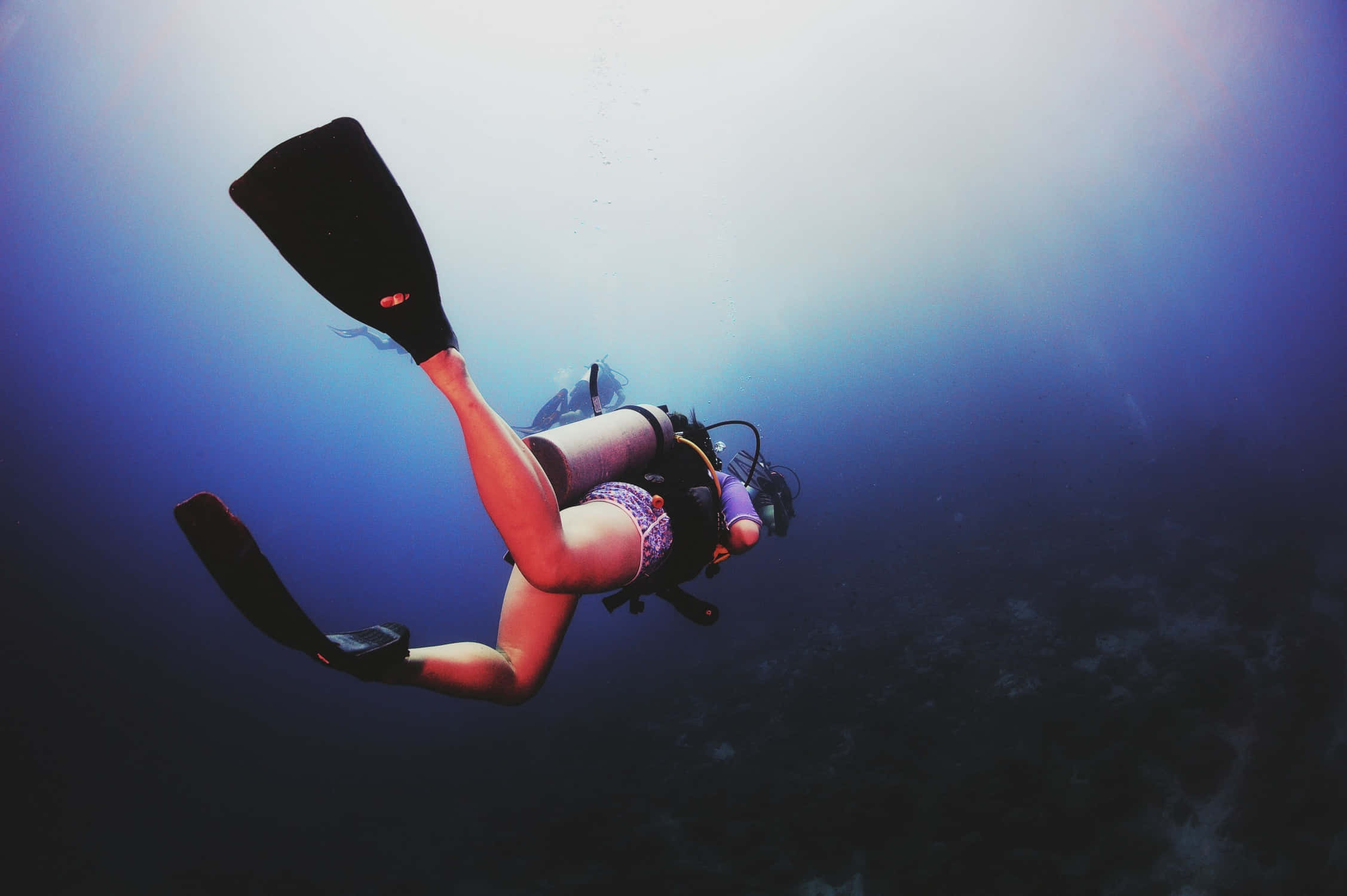diving 桌布 壁紙 — 一名水肺潛水員在深藍色海水中滑行，陽光從上方穿透而下。