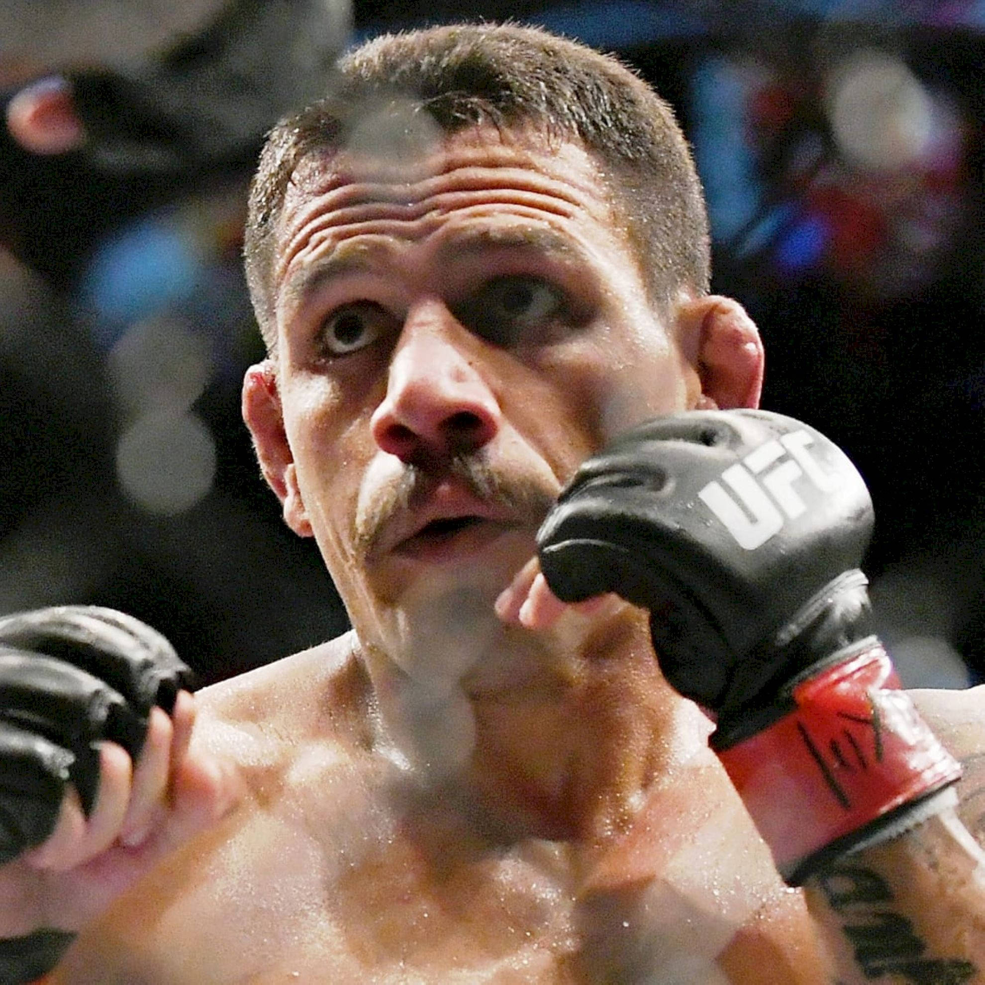 MMA 桌布 壁紙 — 一名汗流浹背、留鬍子的UFC拳手在燈光昏暗的場館中戴著黑色手套，眼神專注。
