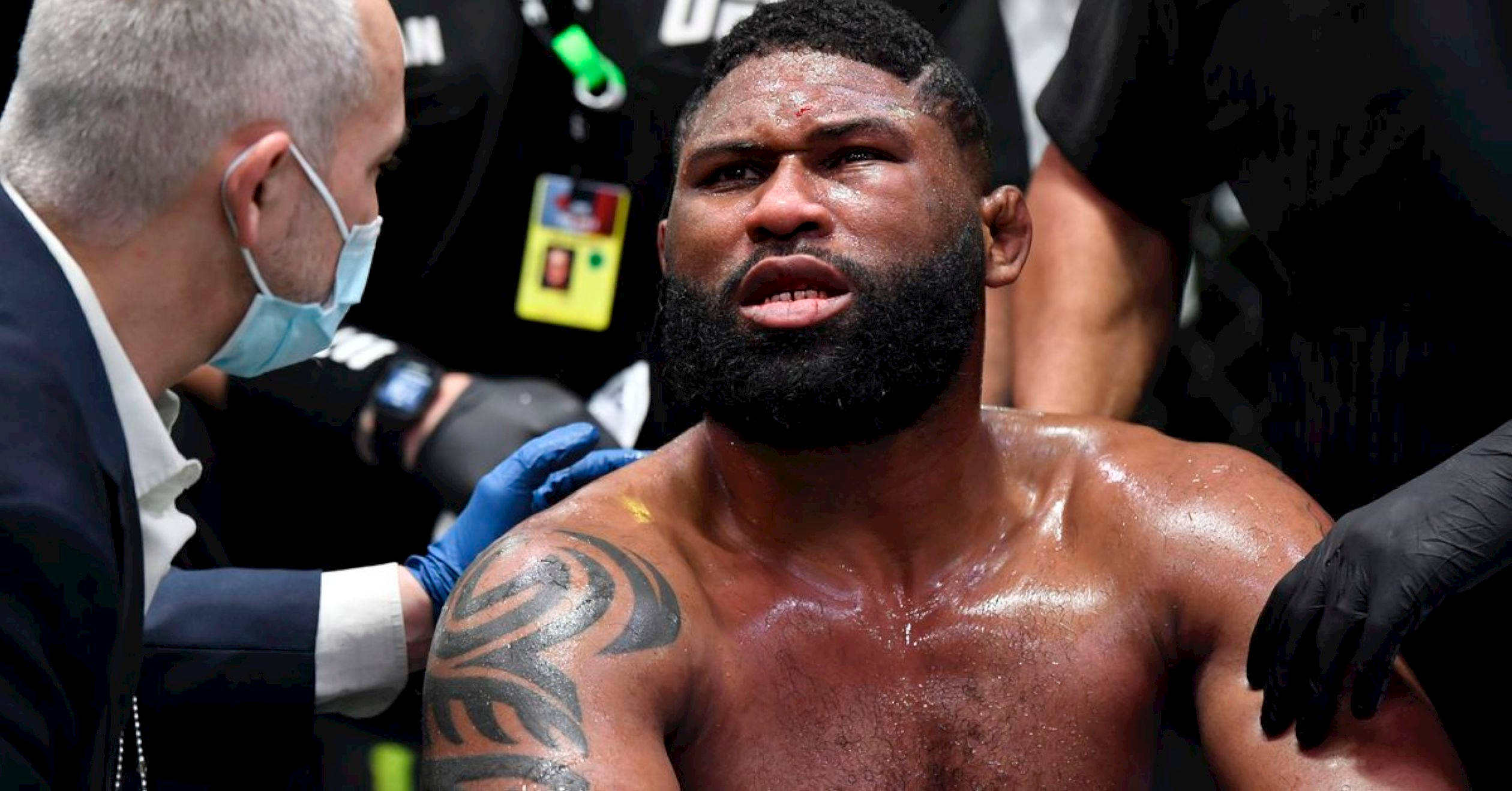 UFC 桌布 壁紙 — 一名汗流浹背、肩上帶有部落紋身的UFC拳手在比賽後正接受醫療人員的照料。