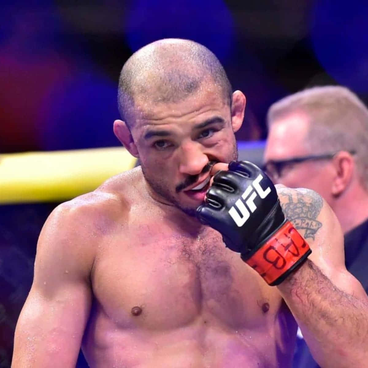 MMA 桌布 壁紙 — 一名汗流浹背的UFC拳手，手臂上有刺青，在明亮的競技場燈光下於八角籠中緊握護齒。