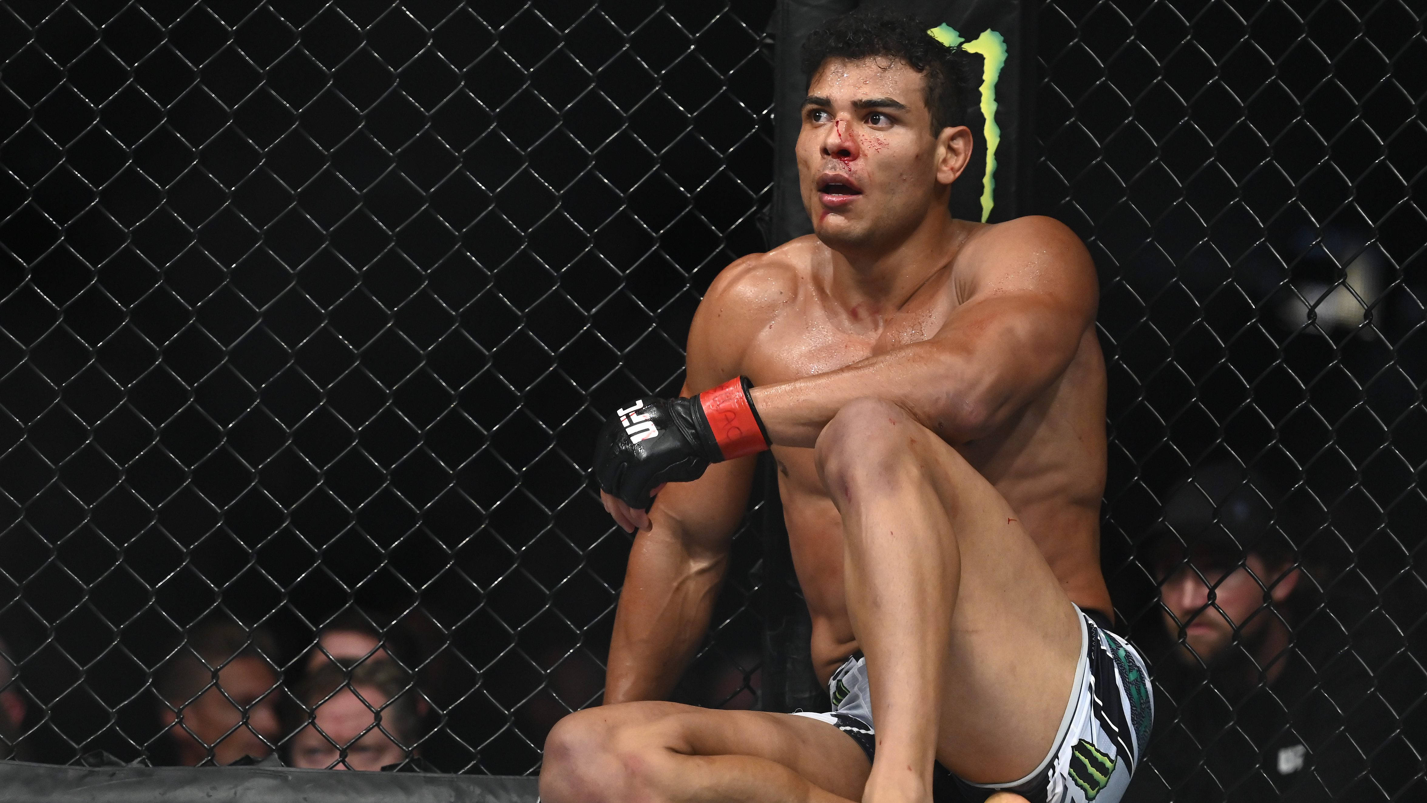 UFC 桌布 壁紙 — 一名汗流浹背的UFC拳手，滿臉是血，眼神專注，疲憊地靠在籠邊。