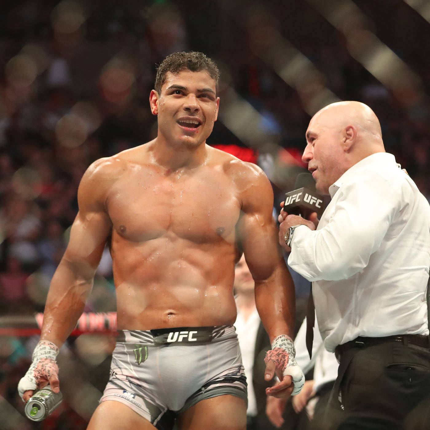UFC 桌布 壁紙 — 一名汗流浹背的UFC拳手在勝利中閃耀，一名光頭記者在擁擠的競技場中將麥克風靠近他的肩膀。