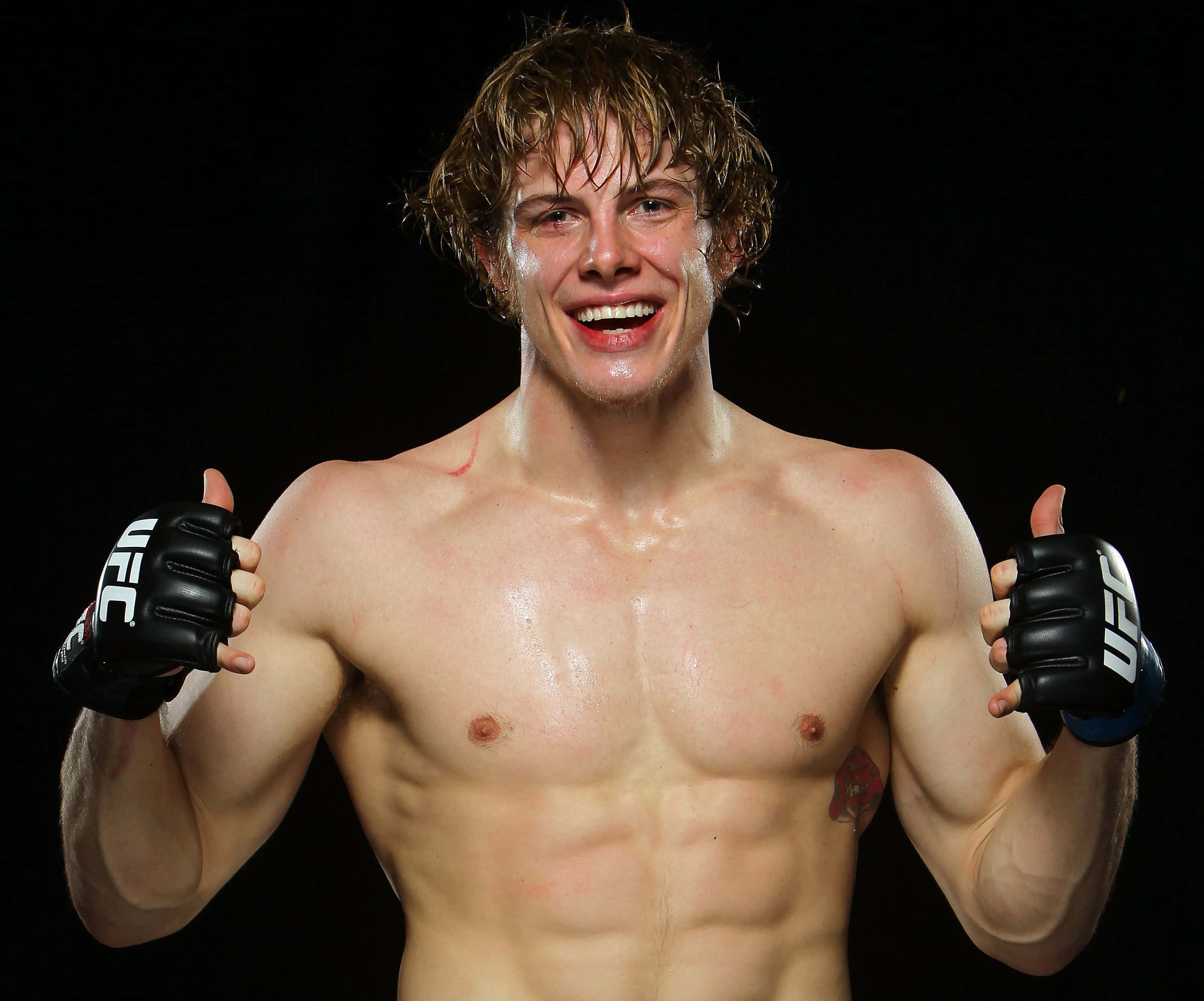UFC 桌布 壁紙 — 一名汗流浹背的UFC拳手在黑色背景前露出勝利的笑容，豎起兩個大拇指。