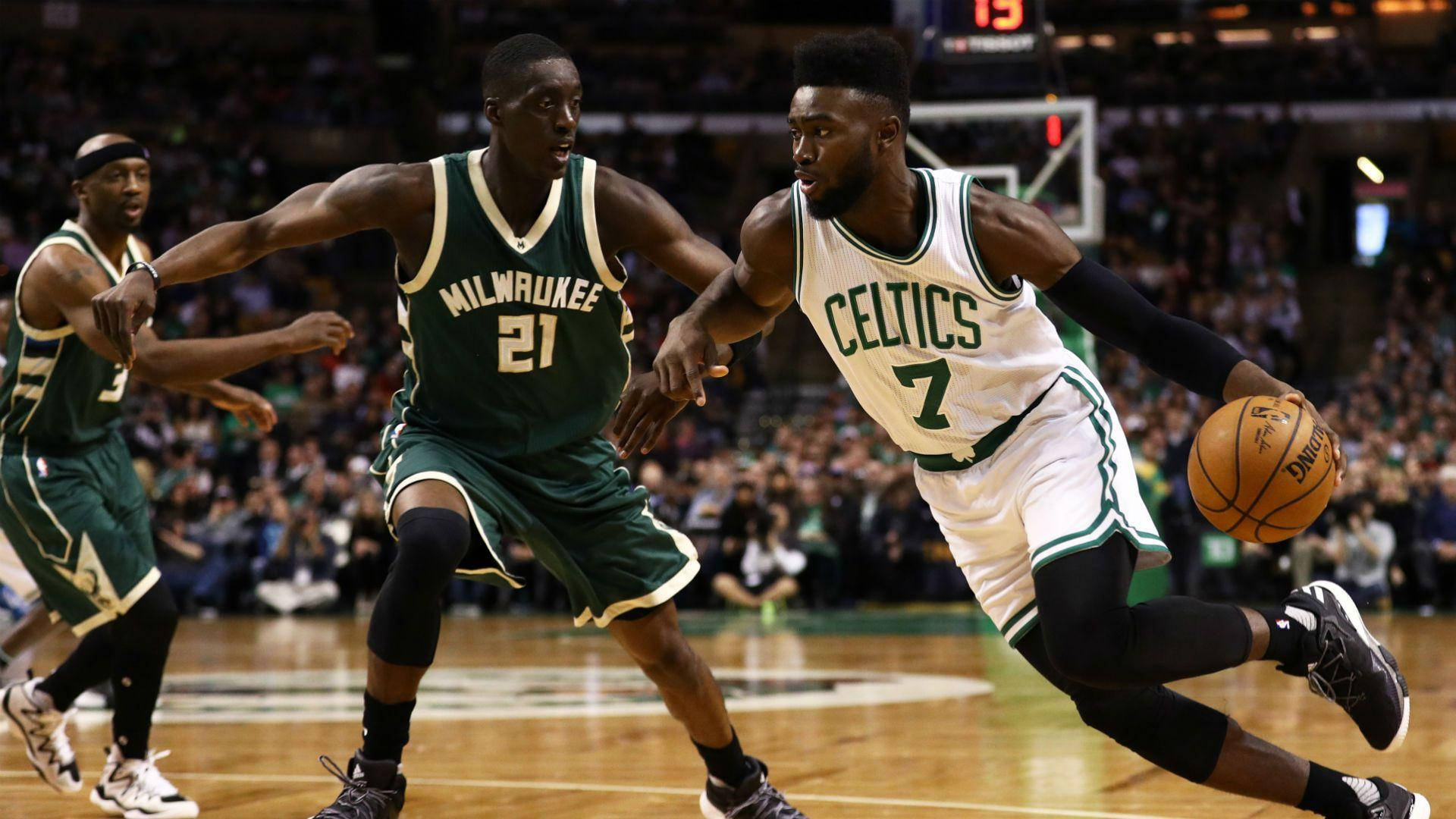 Jaylen Brown 桌布 壁紙 — 一名波士頓塞爾提克球員在激烈的NBA比賽中運球，同時被兩名密爾瓦基公鹿球員緊密防守。