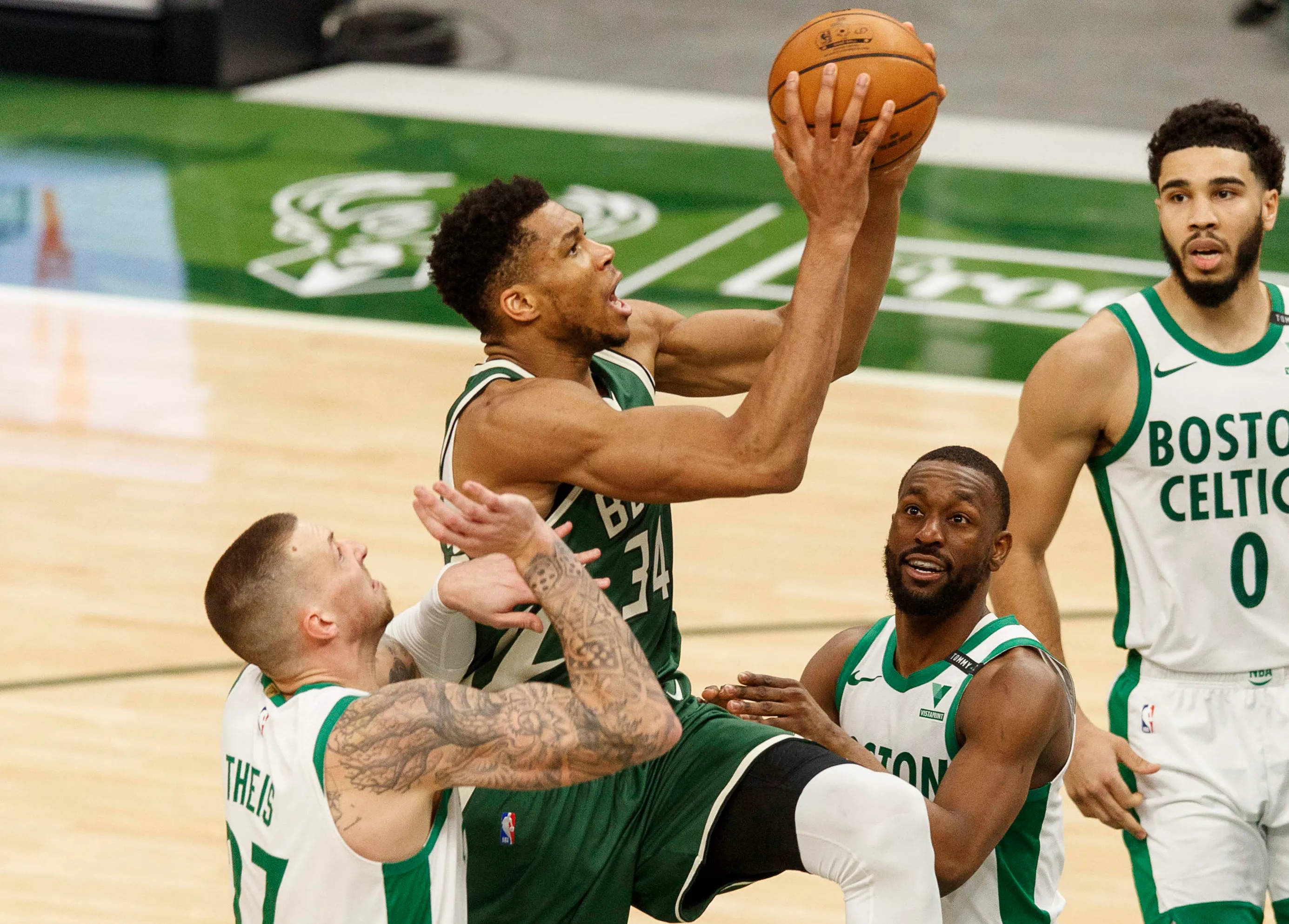 Giannis 桌布 壁紙 — 一名波士頓塞爾提克球員高高跳起投籃，對手在激烈的NBA比賽中試圖干擾投籃。
