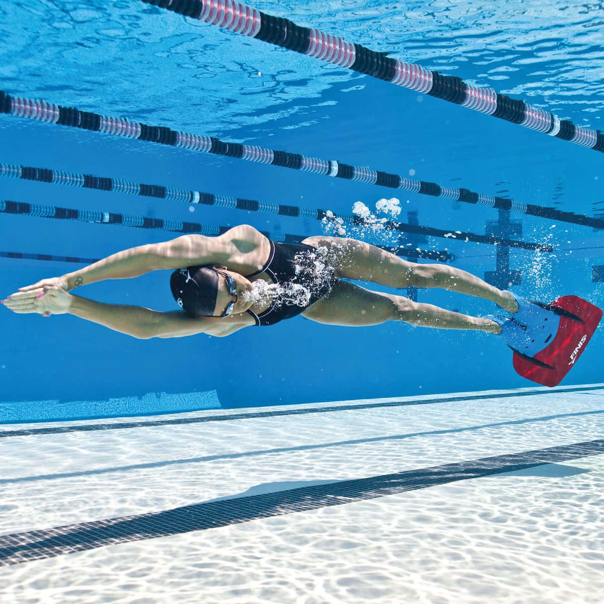 Swimming 桌布 壁紙 — 一名泳者穿著黑色泳衣和紅色蛙鞋，在水池中潛行，身後留下氣泡。