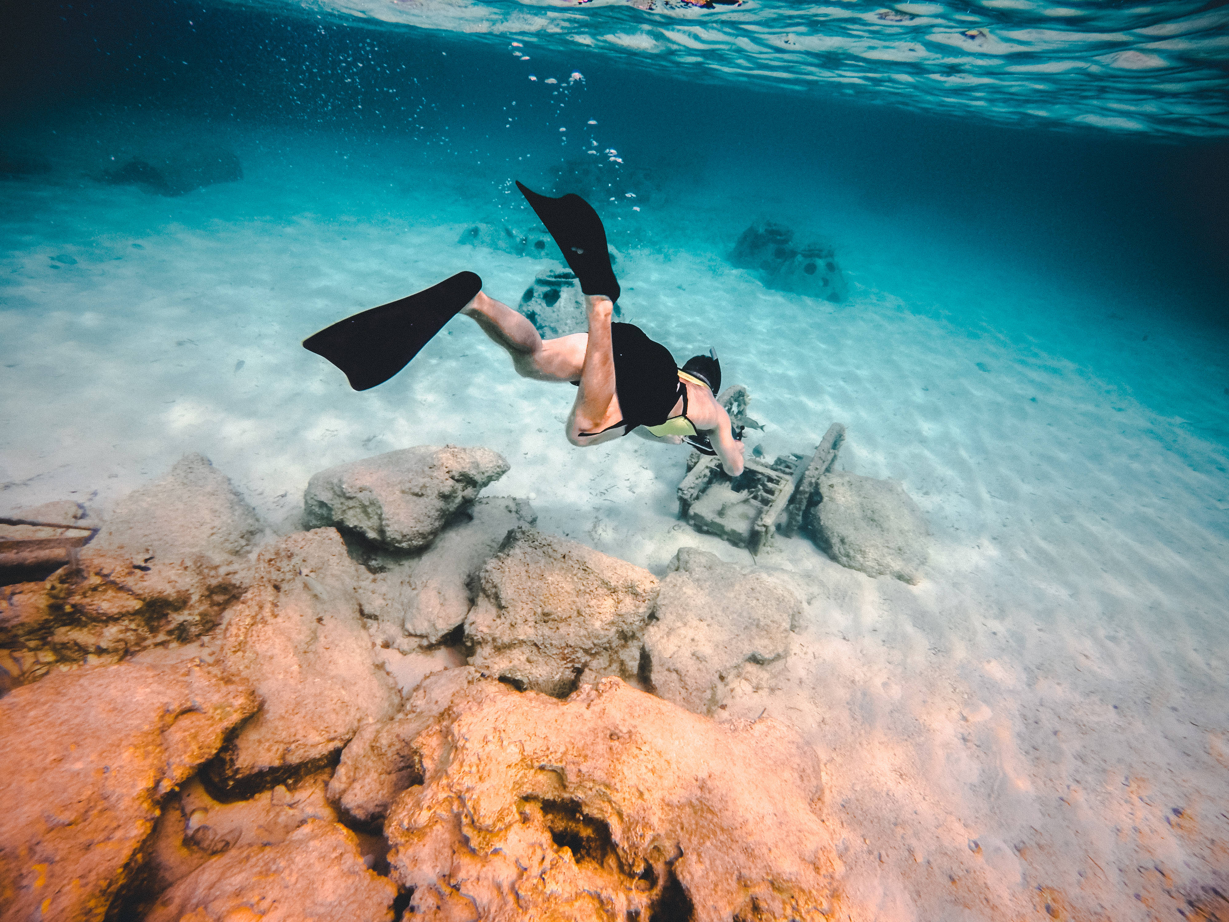 Snorkeling 桌布 壁紙 — 一名浮潛者在清澈碧綠的海水中，優雅地滑過陽光照射的珊瑚石。