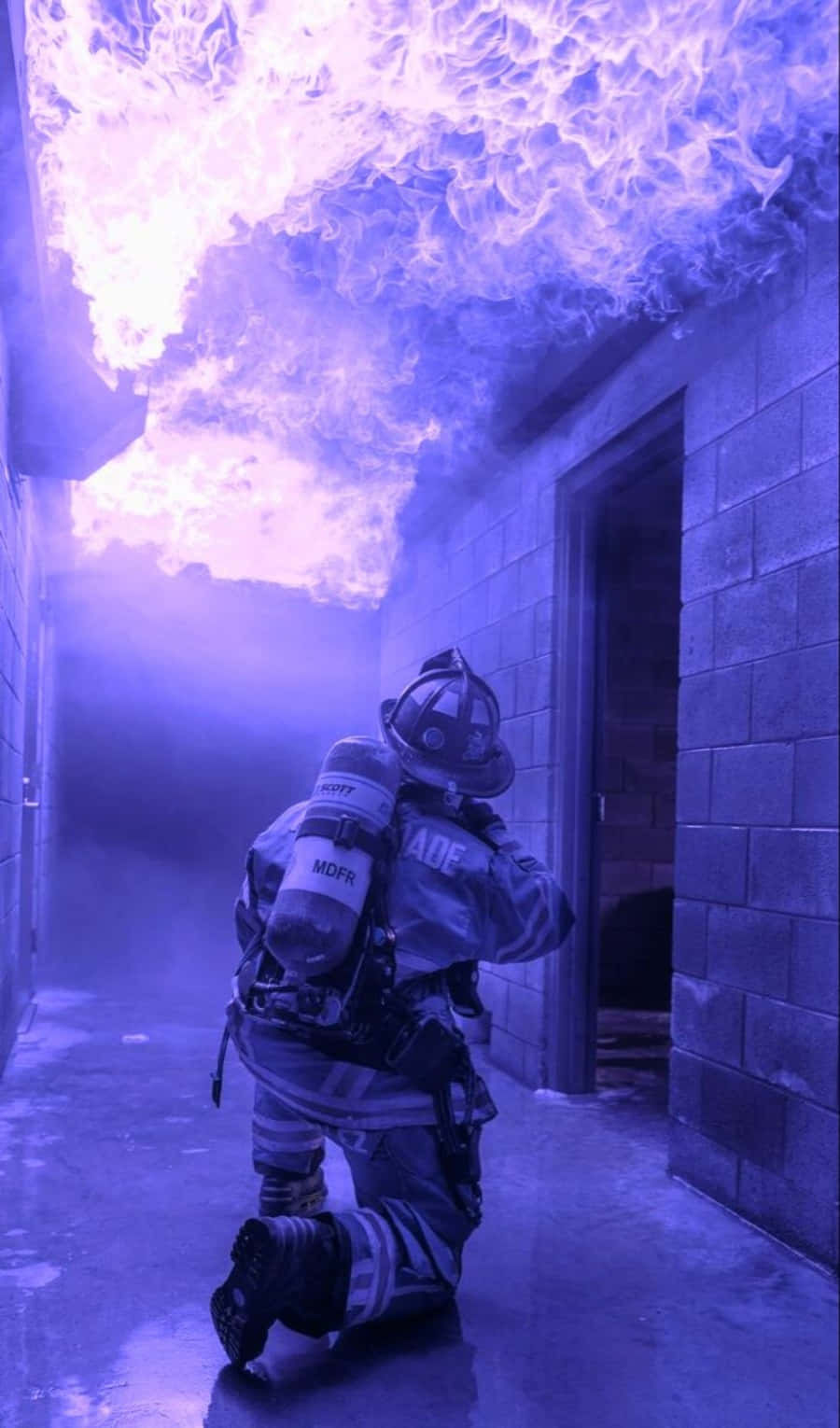Fireman 桌布 壁紙 — 一名消防員跪在煙霧瀰漫的走廊中，上方天花板噴出強烈的紫色火焰。