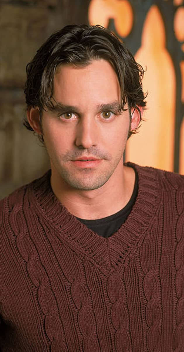 Nicholas Brendon 桌布 壁紙 — 一名深色波浪髮、眼神銳利的男子，穿著質感豐富的棗紅色絞花針織毛衣，背景溫暖模糊。