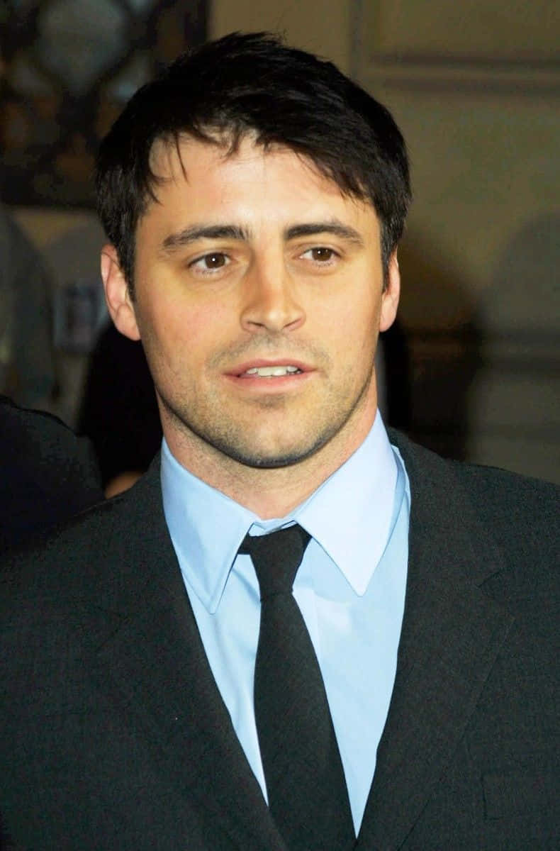 Matt Leblanc 桌布 壁紙 — 一名深色頭髮男士的近距離肖像，身穿黑色西裝、淺藍色襯衫和黑色領帶。