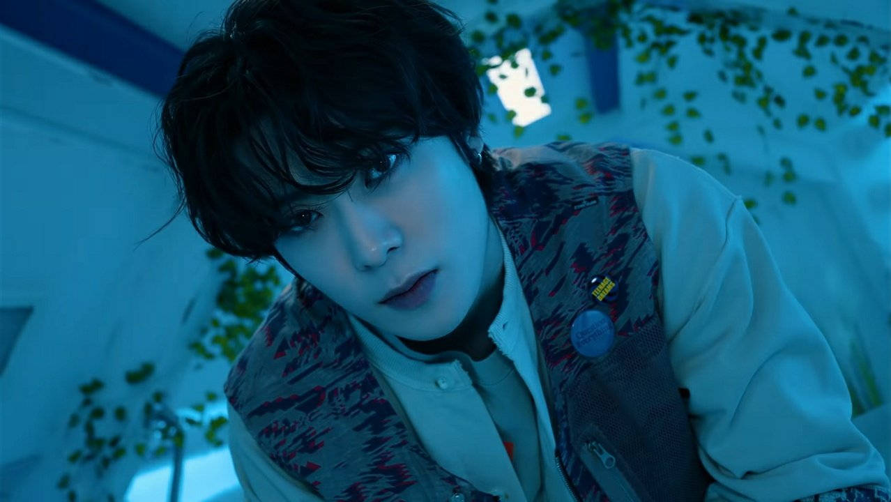 Nct 桌布 壁紙 — 一名深色頭髮的年輕男子在冷藍色燈光下，被綠色藤蔓環繞的場景中專注地凝視。