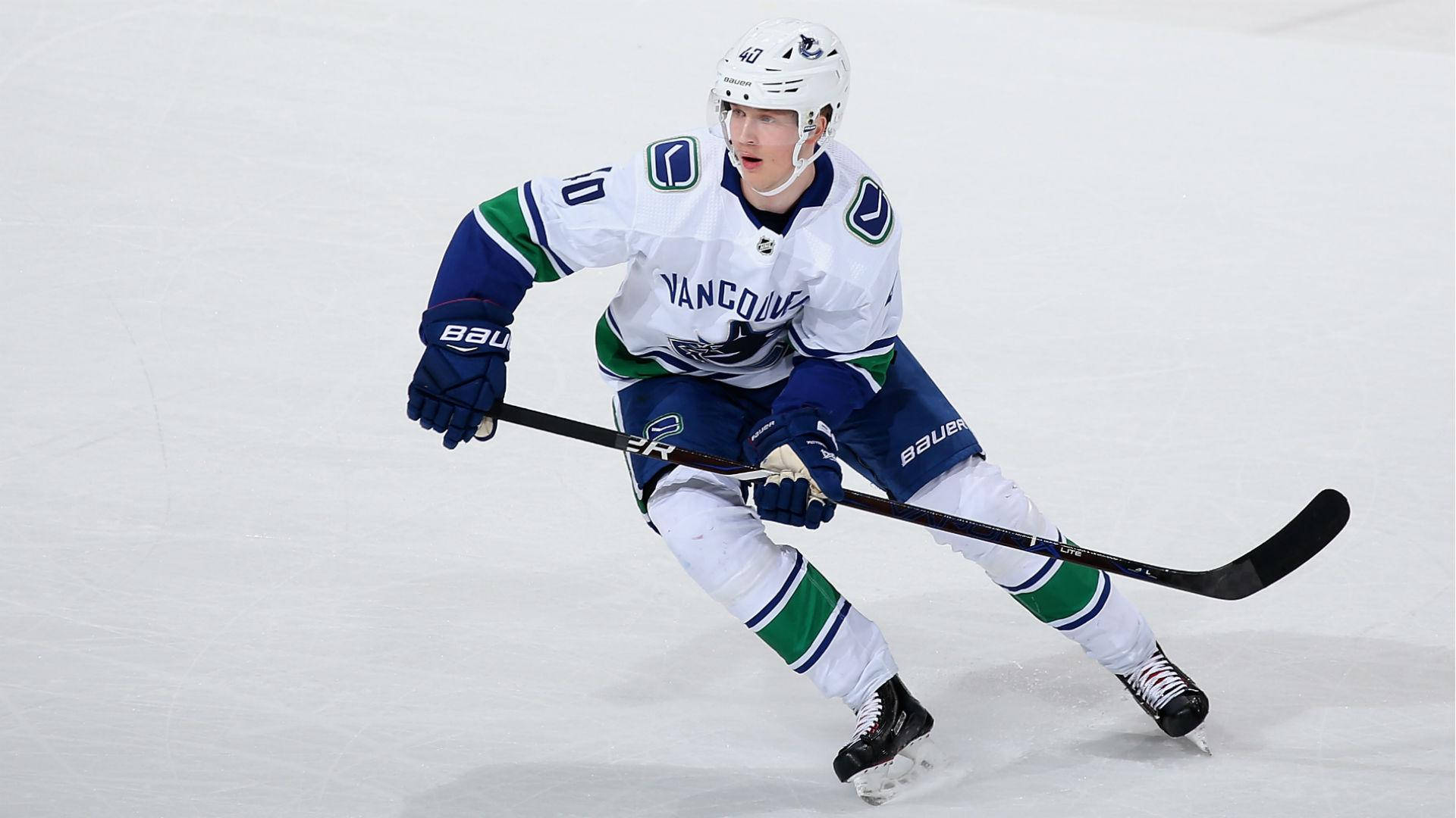 hockey 桌布 壁紙 — 一名溫哥華加人隊（Vancouver Canucks）冰球運動員身穿白、藍、綠色球衣，在比賽中手持球桿在冰上激烈滑行。