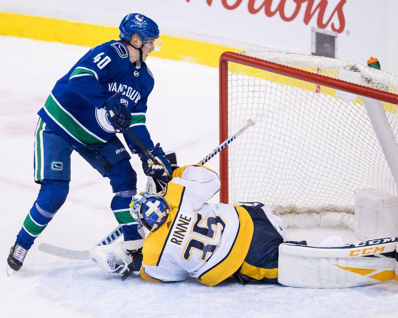 hockey 桌布 壁紙 — 一名溫哥華加人隊球員在激烈的冰球比賽中滑過倒地的納什維爾掠奪者隊守門員。