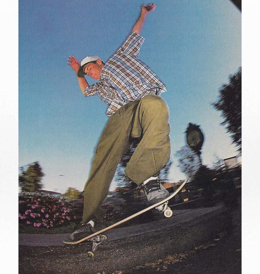 Retro Skateboard 桌布 壁紙 — 一名滑板手在半空中，在清晰藍天和模糊背景動態下表演技巧。