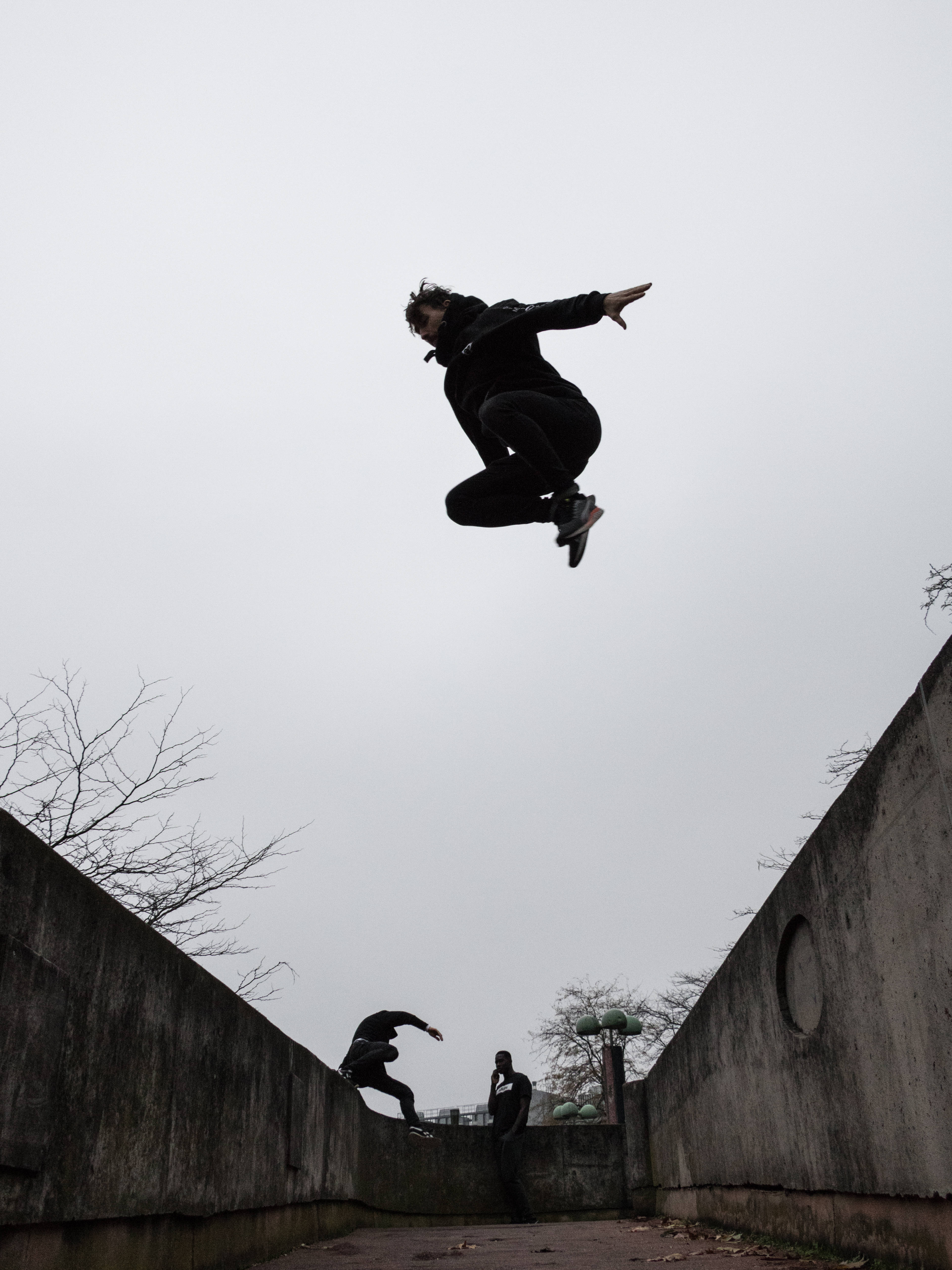 Parkour 桌布 壁紙 — 一名滑板手在半空中，在陰天下的混凝土坡道上表演技巧。